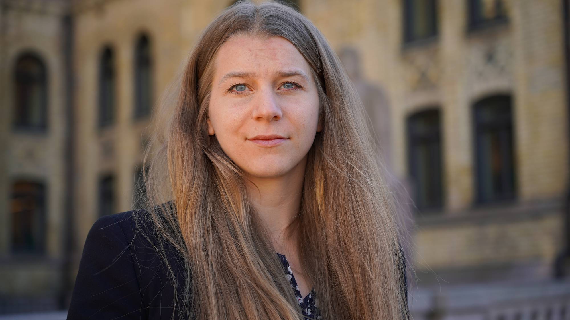 Kvinne med langt hår ser i kamera