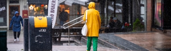 En person går med gul regnjakke i regnværet i Tønsberg sentrum.