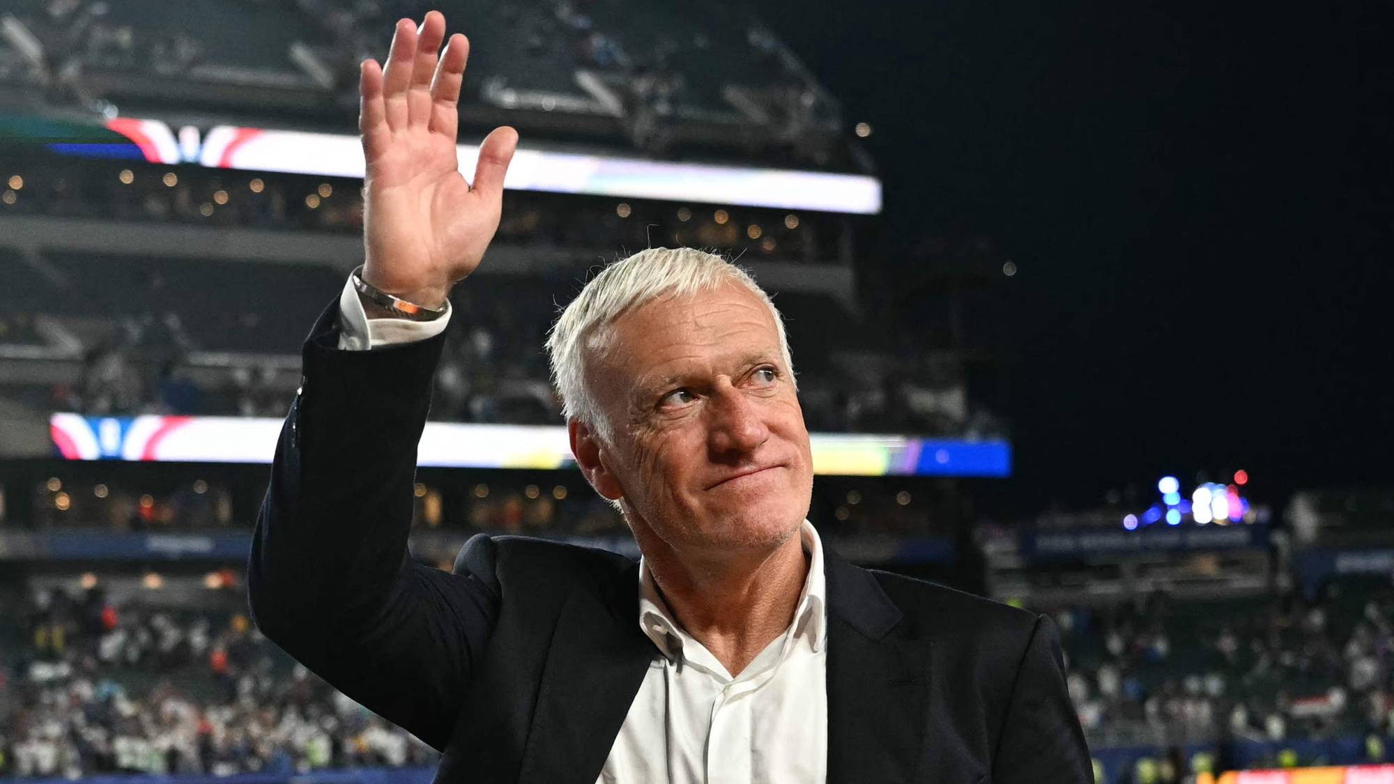 Didier Deschamps vinker til publikum på et fotballstadion. (Bildebeskrivelsen er laget av en KI-tjeneste)