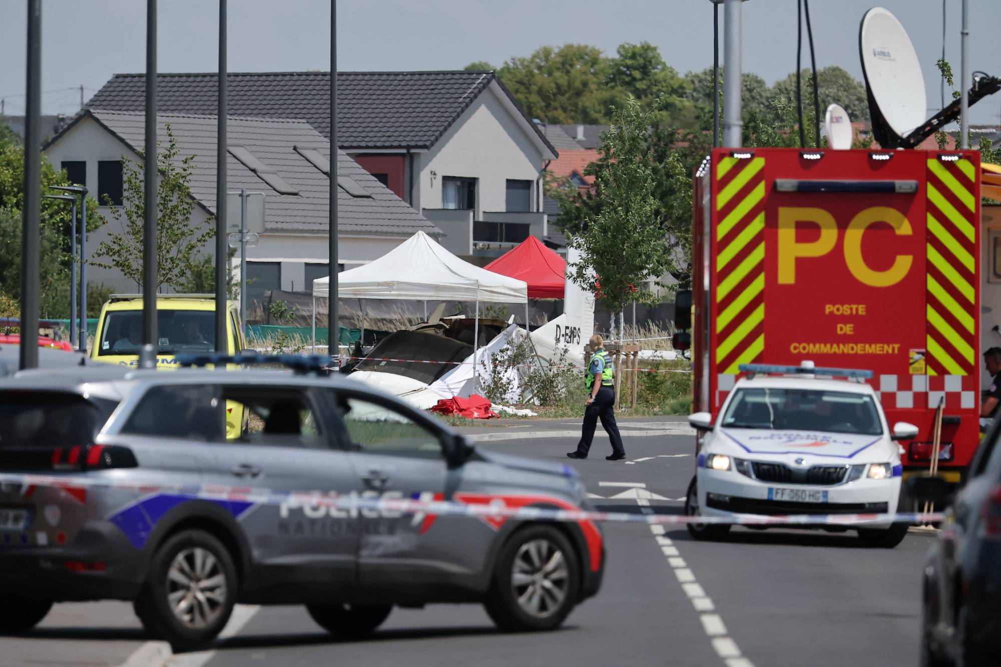 Politiet sperrer av et område ved et småflyulykkessted med telt og utrykningskjøretøy. (Bildebeskrivelsen er laget av en KI-tjeneste)