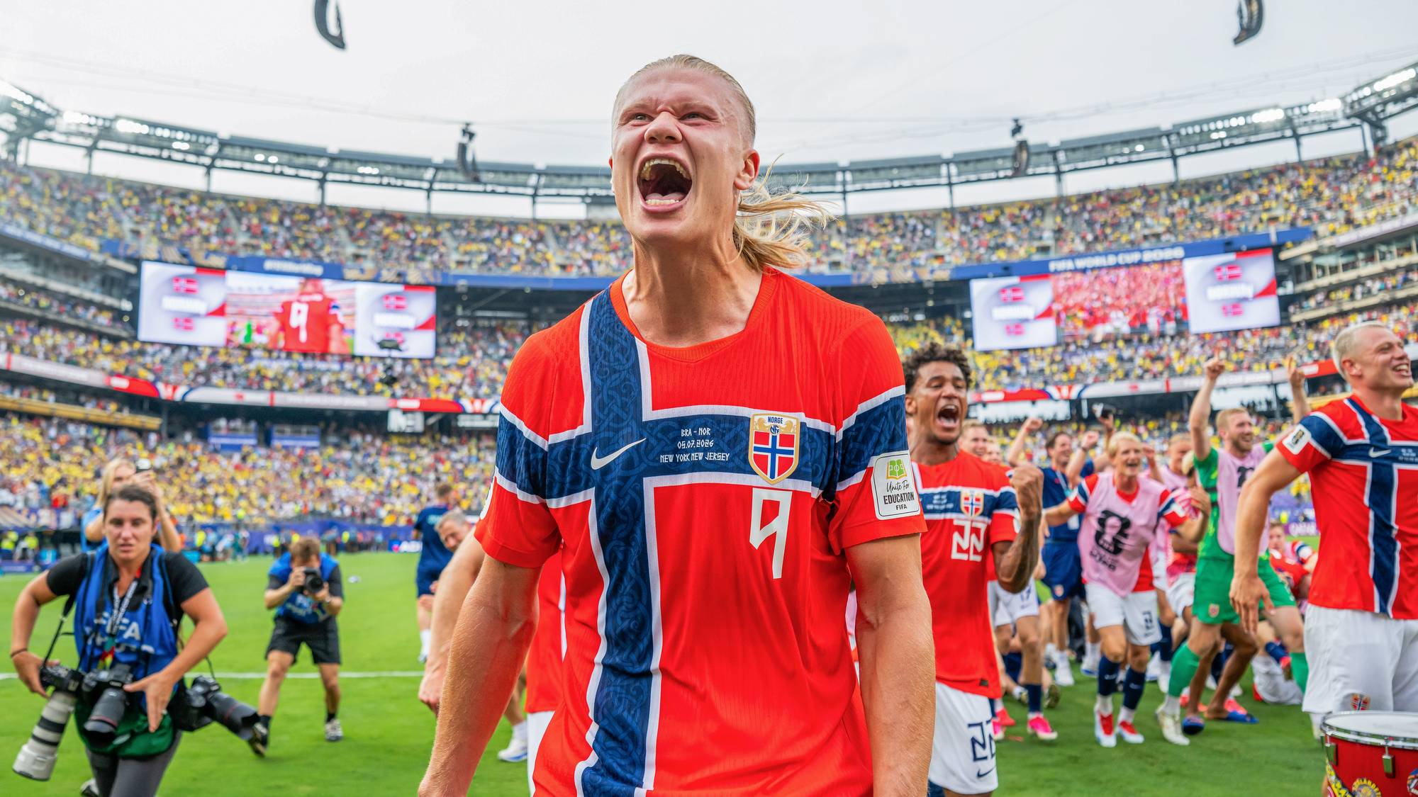 Erling Braut Haaland jubler i norsk landslagsdrakt på en fullsatt fotballstadion. (Bildebeskrivelsen er laget av en KI-tjeneste)