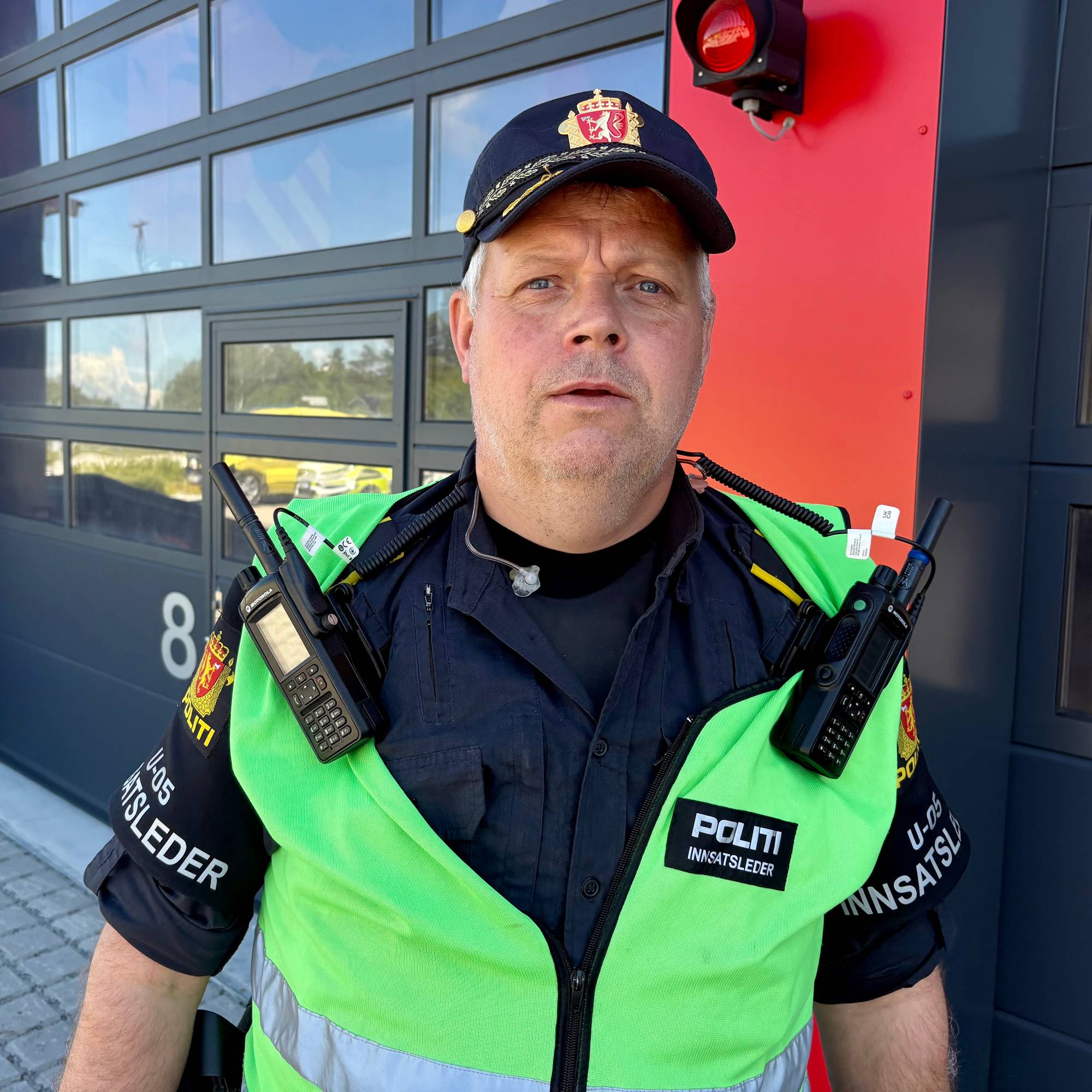 En uniformert politimann står foran en garasjeport.