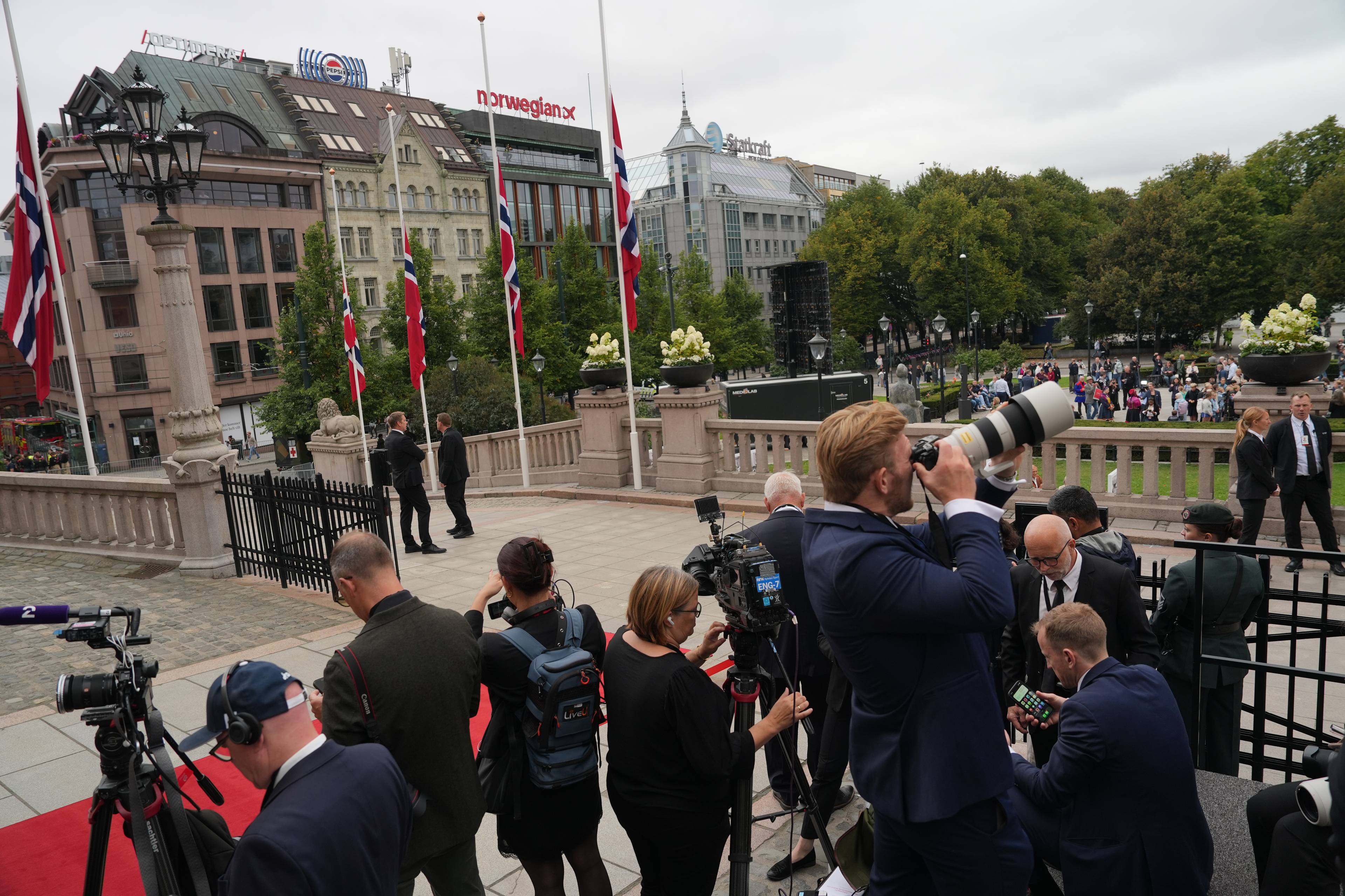 Presse og flagg på halv stang foran Stortinget