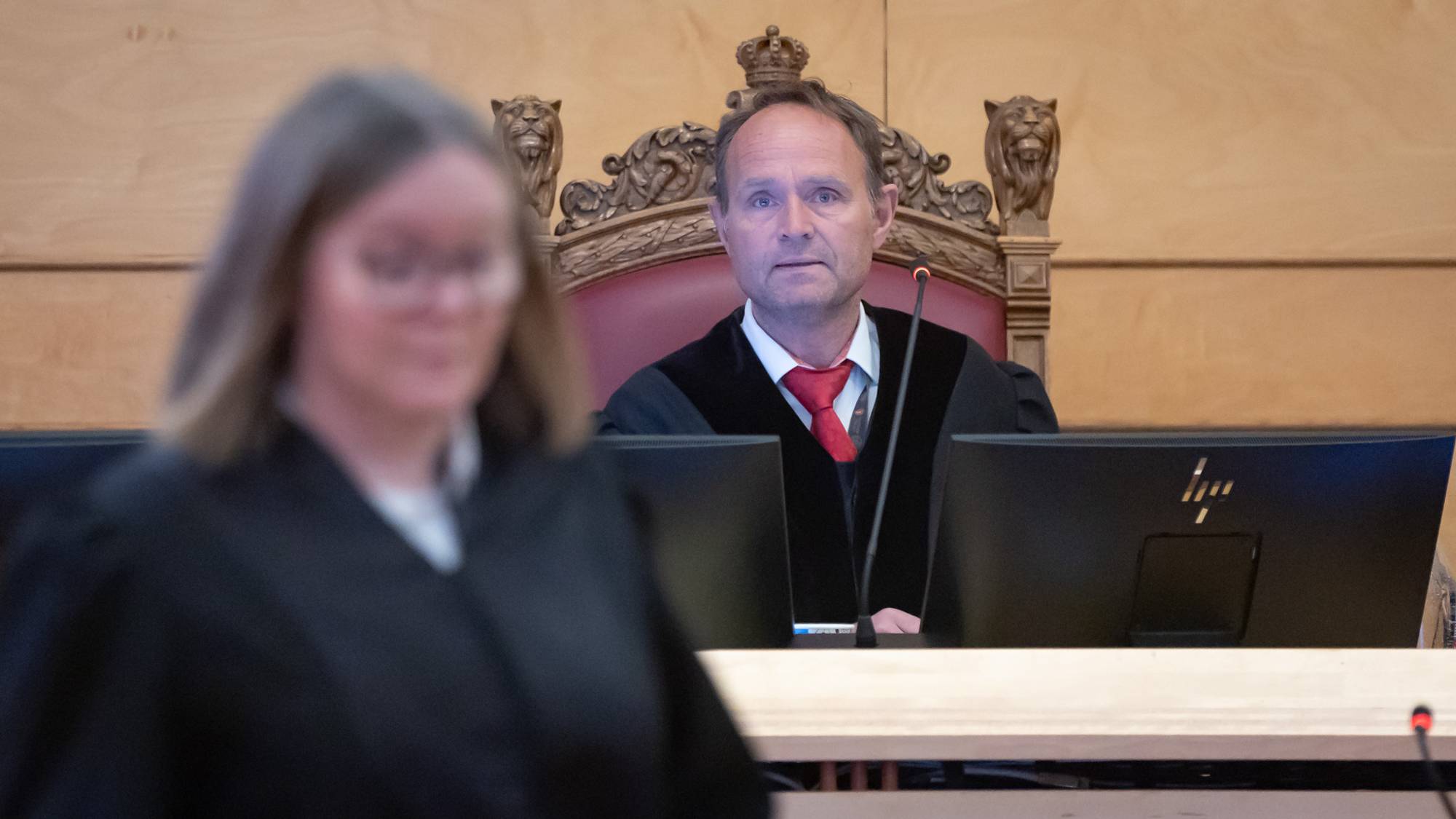Tingrettsdommer Eirik Lereim sitter i dommerstolen. I forkant av bildet ser vi statsadvokat Eli Reberg Nessimo. Hun passerer foran Lereim. Fokus i bildet er på Lereim