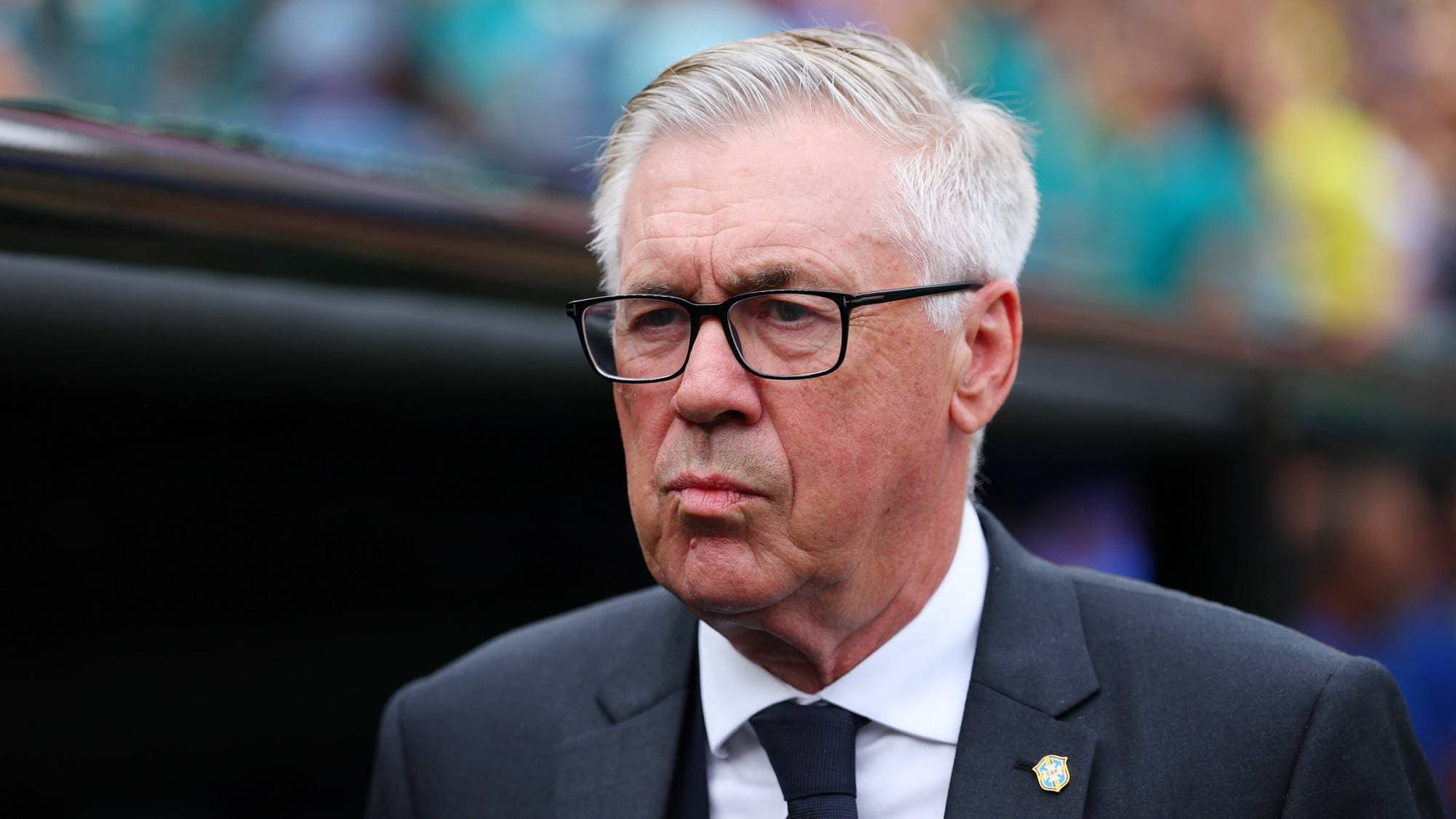 Fotballtrener Carlo Ancelotti i dress med slips, sett foran en fotballarena. (Bildebeskrivelsen er laget av en KI-tjeneste)