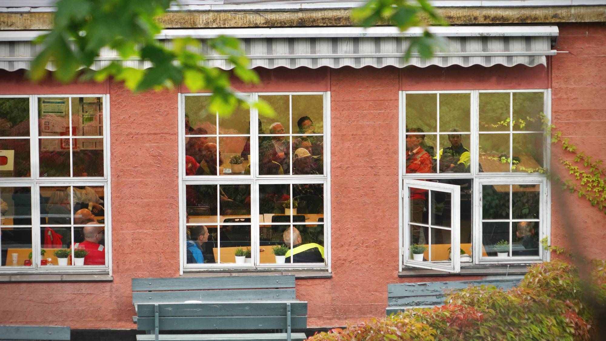 En bygning med mange vinduer. Flere mennesker sitter inne i bygningen,