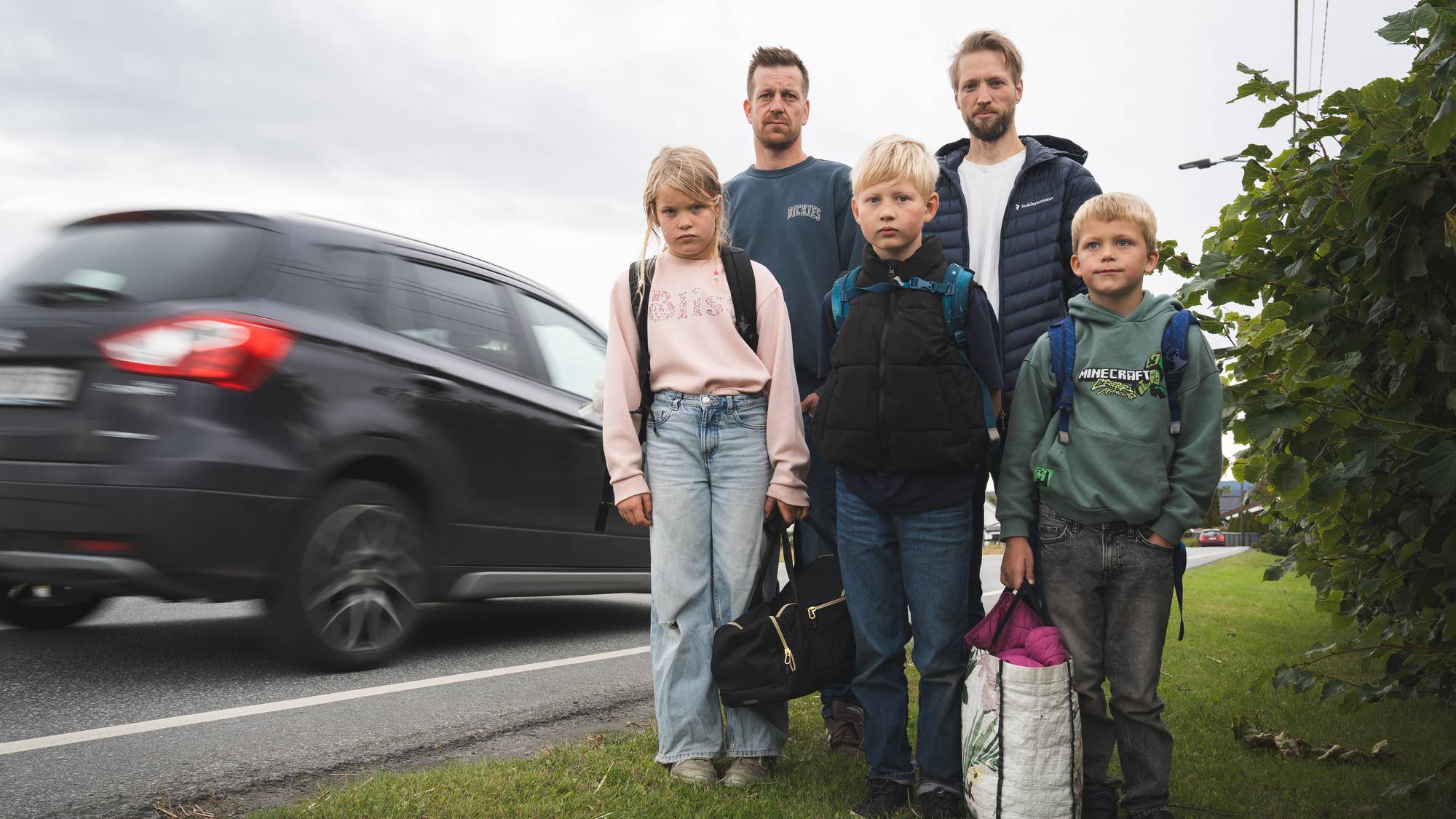 To familier foran bilvei, to foreldre og tre barn