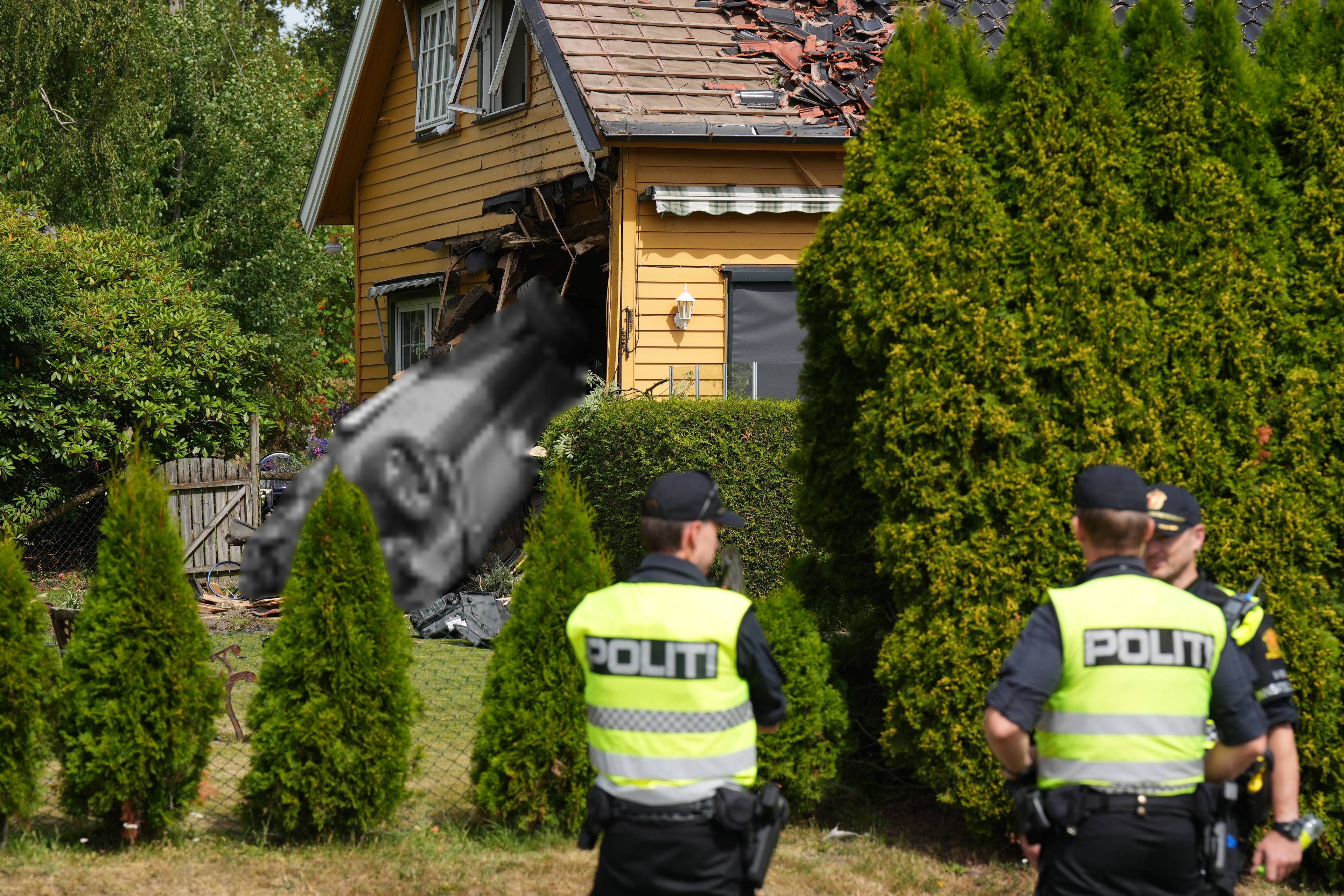 Politifolk står foran huset der en bil har kjørt i veggen