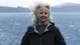 Clio Nelson / privat En dame med grått hår som blåser i vinden, ser mot kamera. I bakgrunn synes en fjord og blånende fjell.