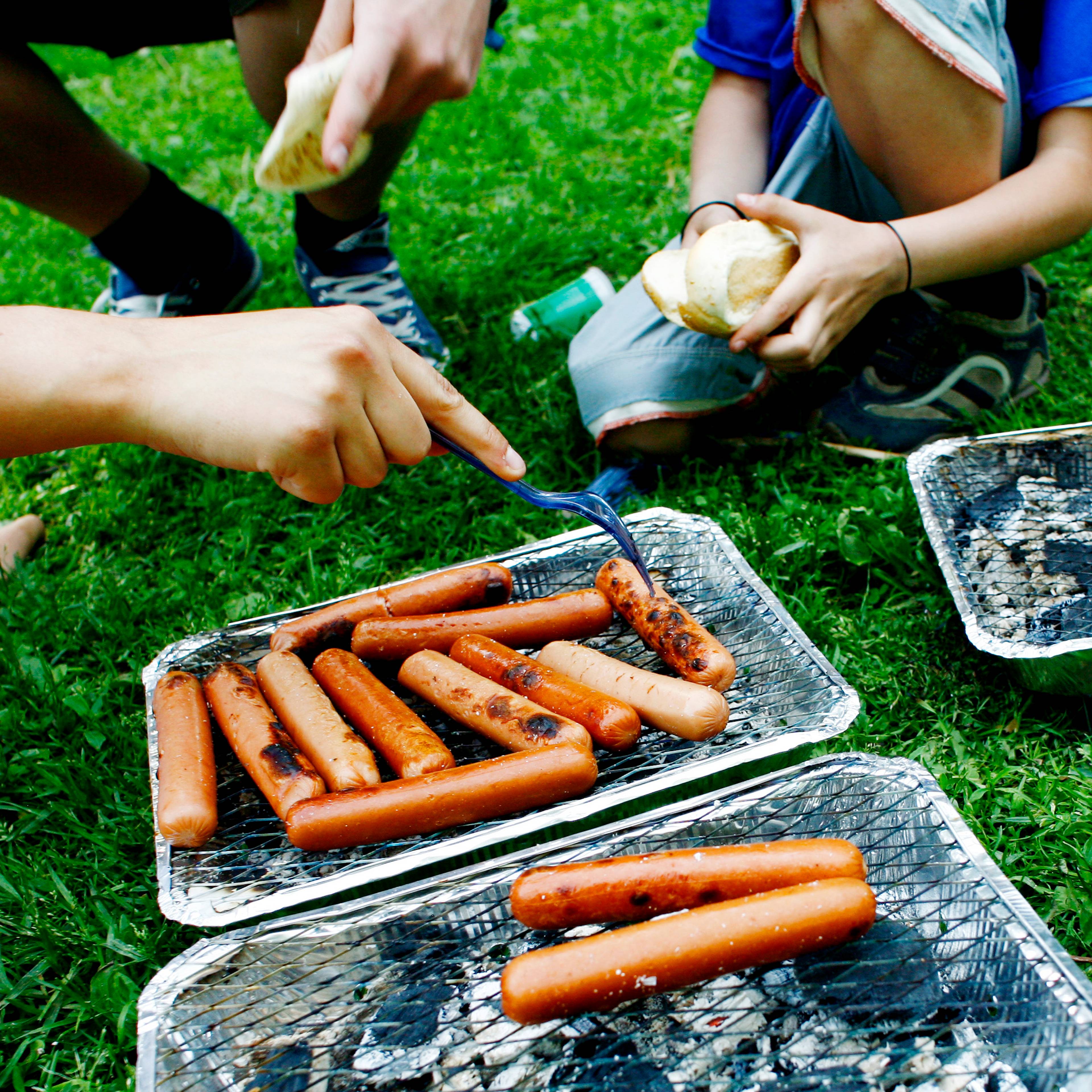 En gruppe mennesker som griller pølse i en park