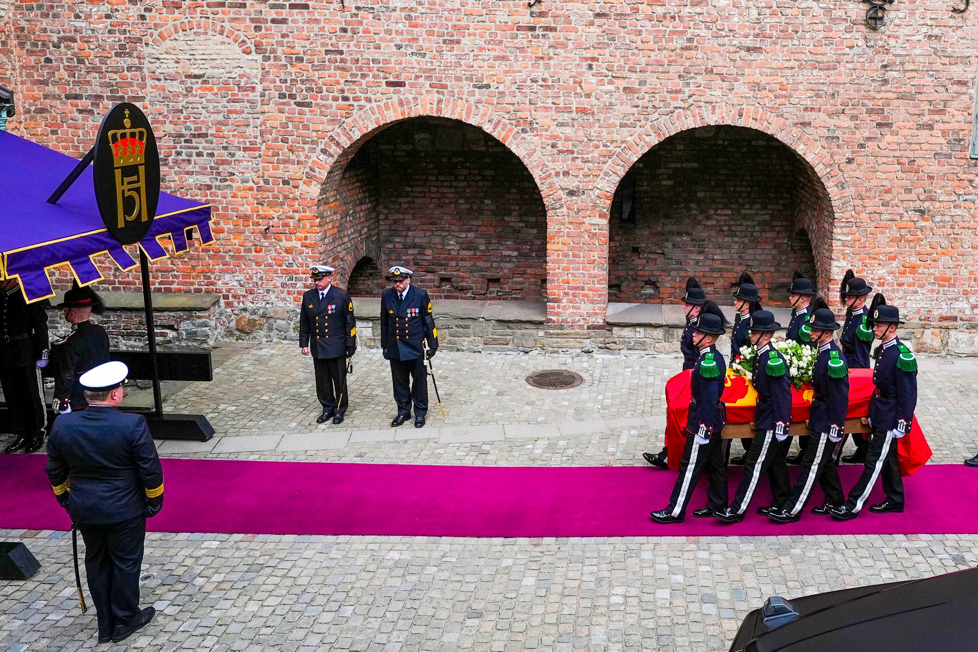 Åtte gardister bærer kong Haralds båre inn i Akershus slottskirke.