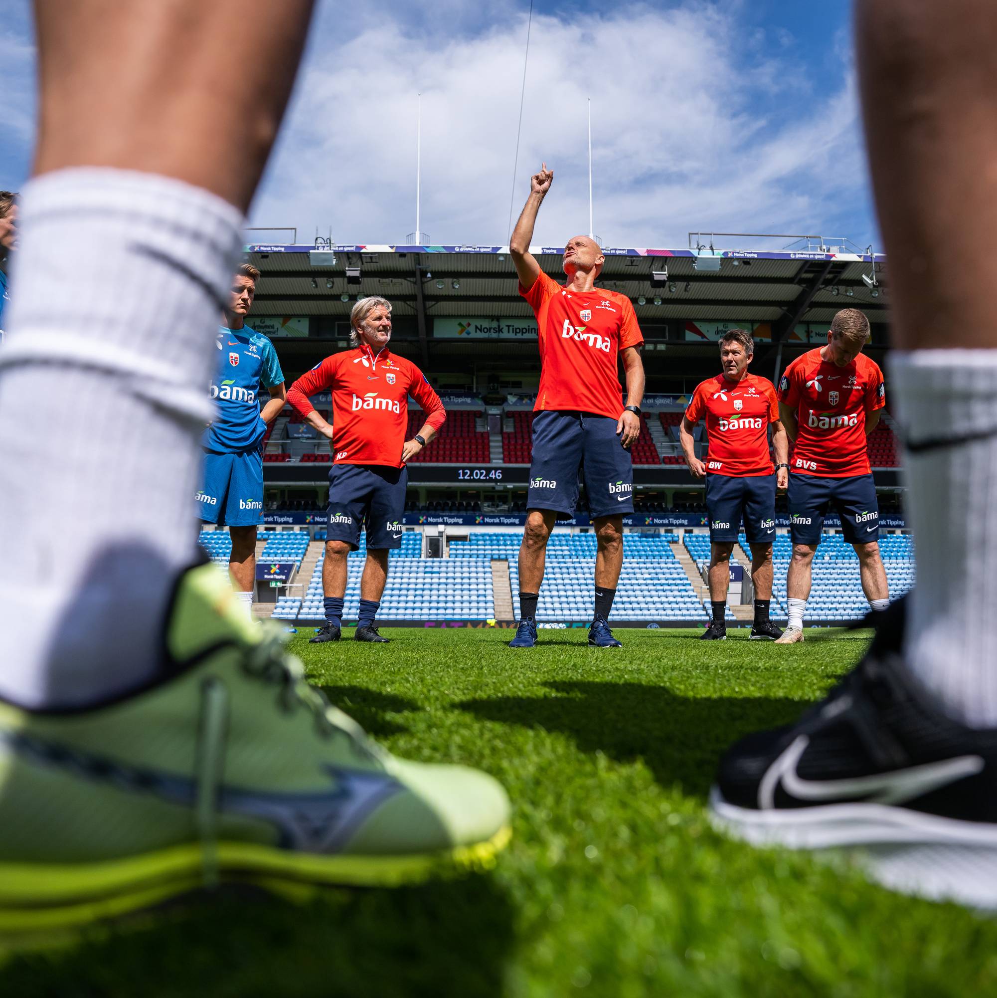 Kent Bergersen og Ståle Solbakken på treningsfeltet med to par bein i forgrunnen