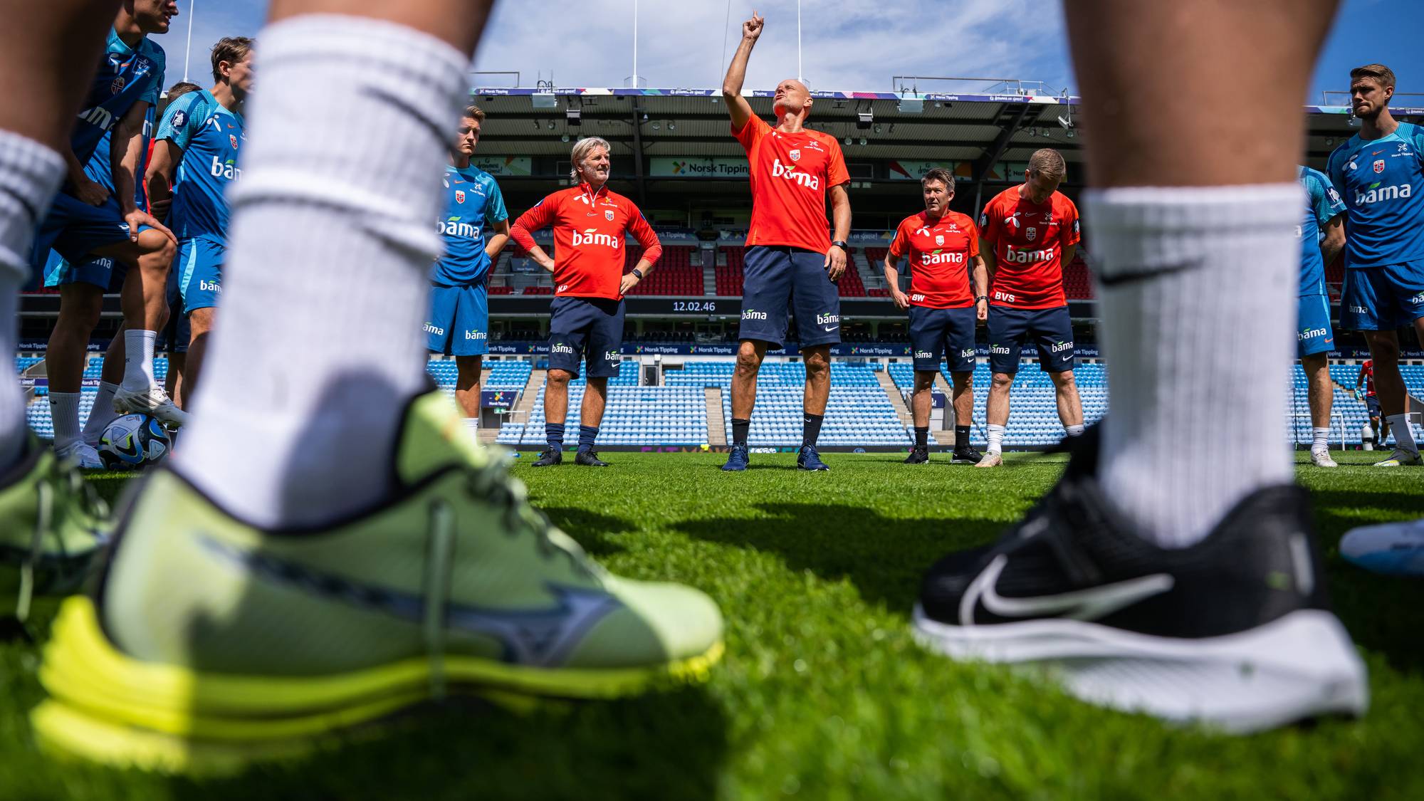 Kent Bergersen og Ståle Solbakken på treningsfeltet med to par bein i forgrunnen