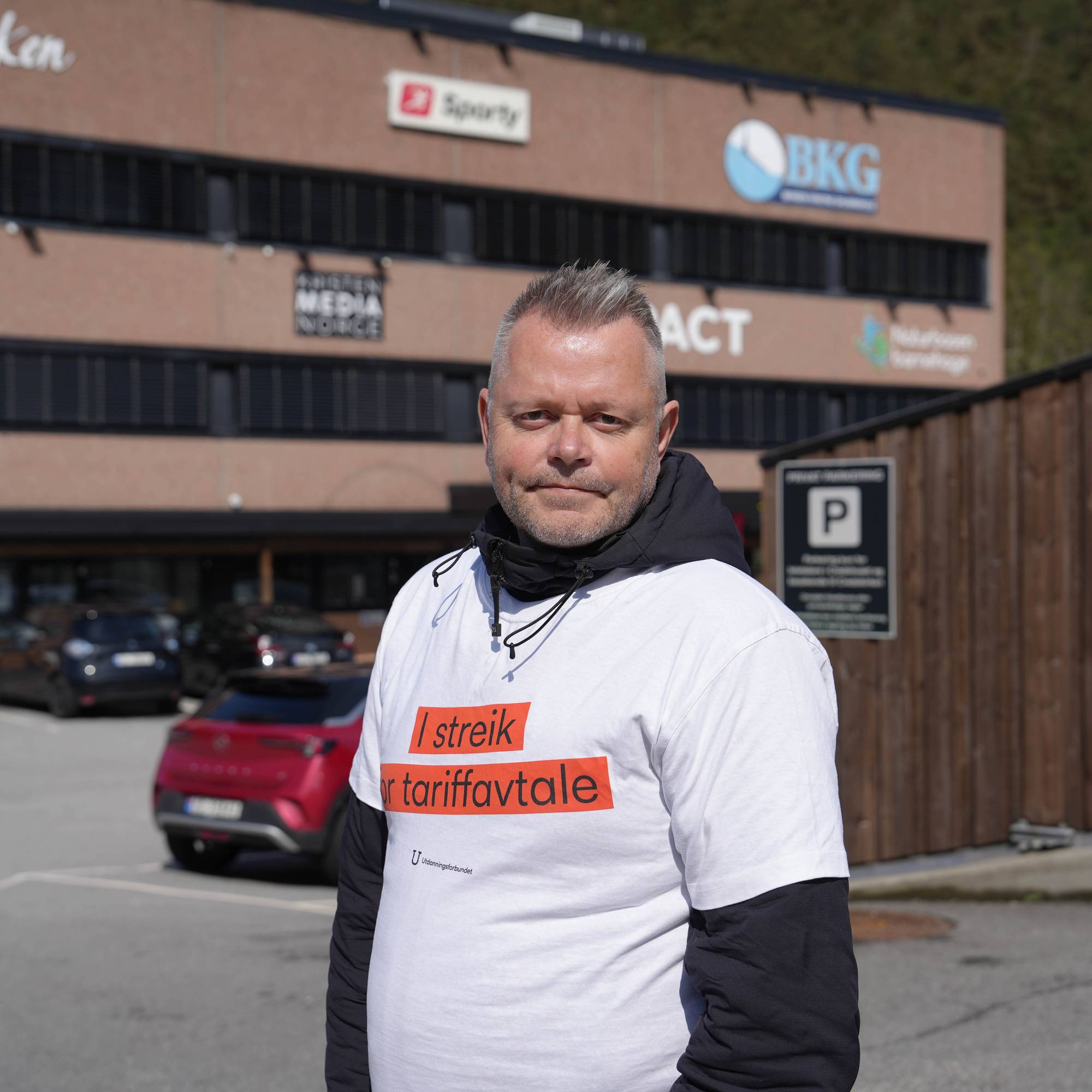 Styreleiar i Utdanningsforbundet Vestland, Steinar Vegsund Strømsli, står i sentrum av biletet. Han har på seg ei t-skjorte der det står "i streik for tariffavtale". I bakgrunnen ser vi eit brunt bygg med logoen til Credokirken og Bergen Kristne Grunnskole. 