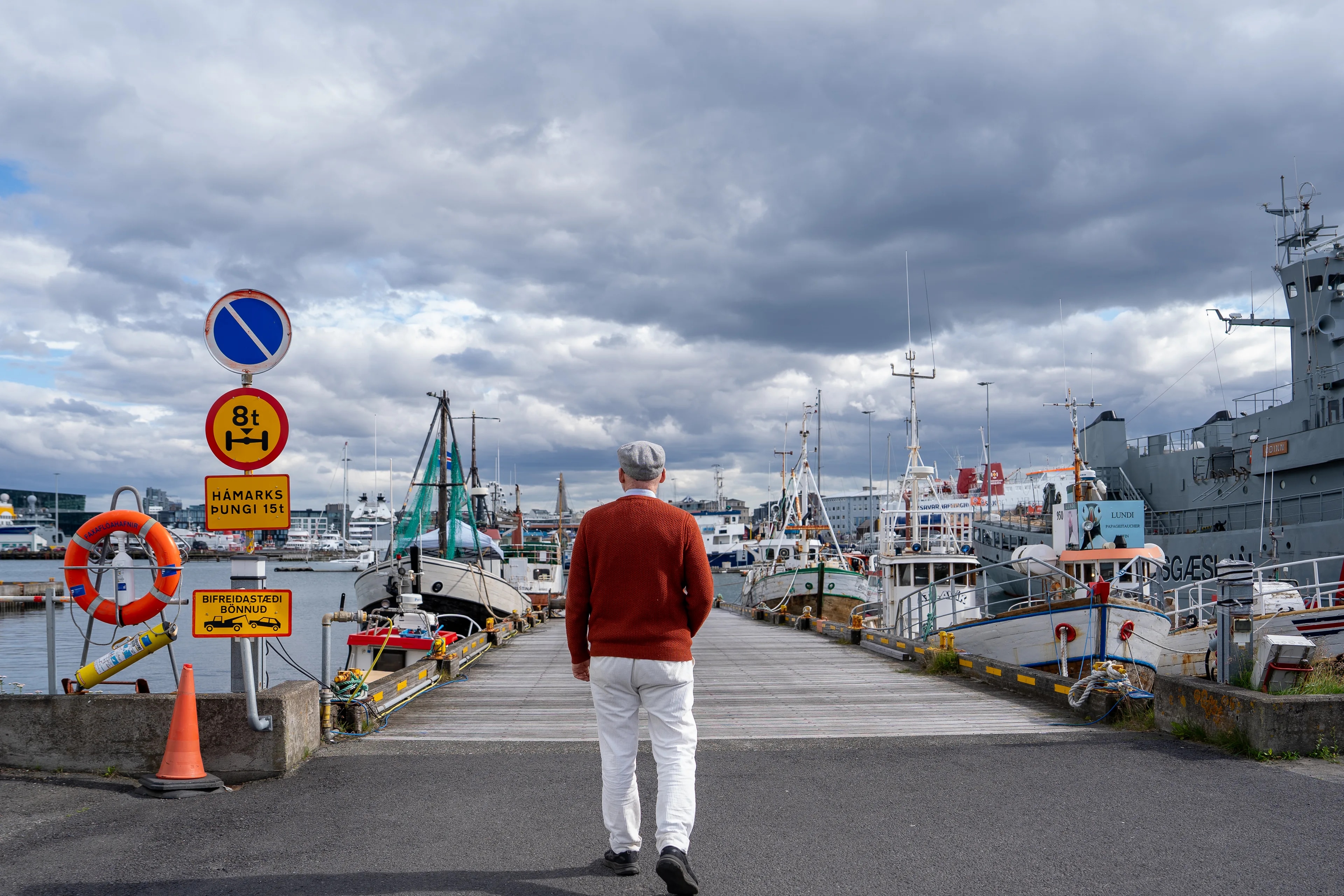 en person som går på en vei nær en havn (Bildebeskrivelsen er laget av en KI-tjeneste)