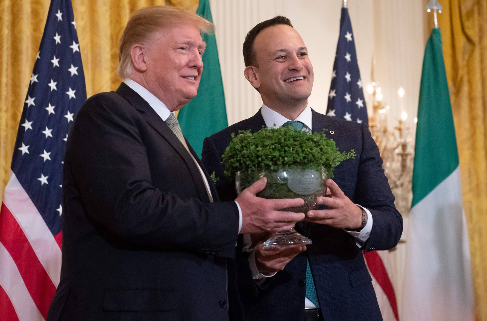 Donald Trump og Leo Varadkar holder en bolle med kløver foran amerikanske og irske flagg. (Bildebeskrivelsen er laget av en KI-tjeneste)