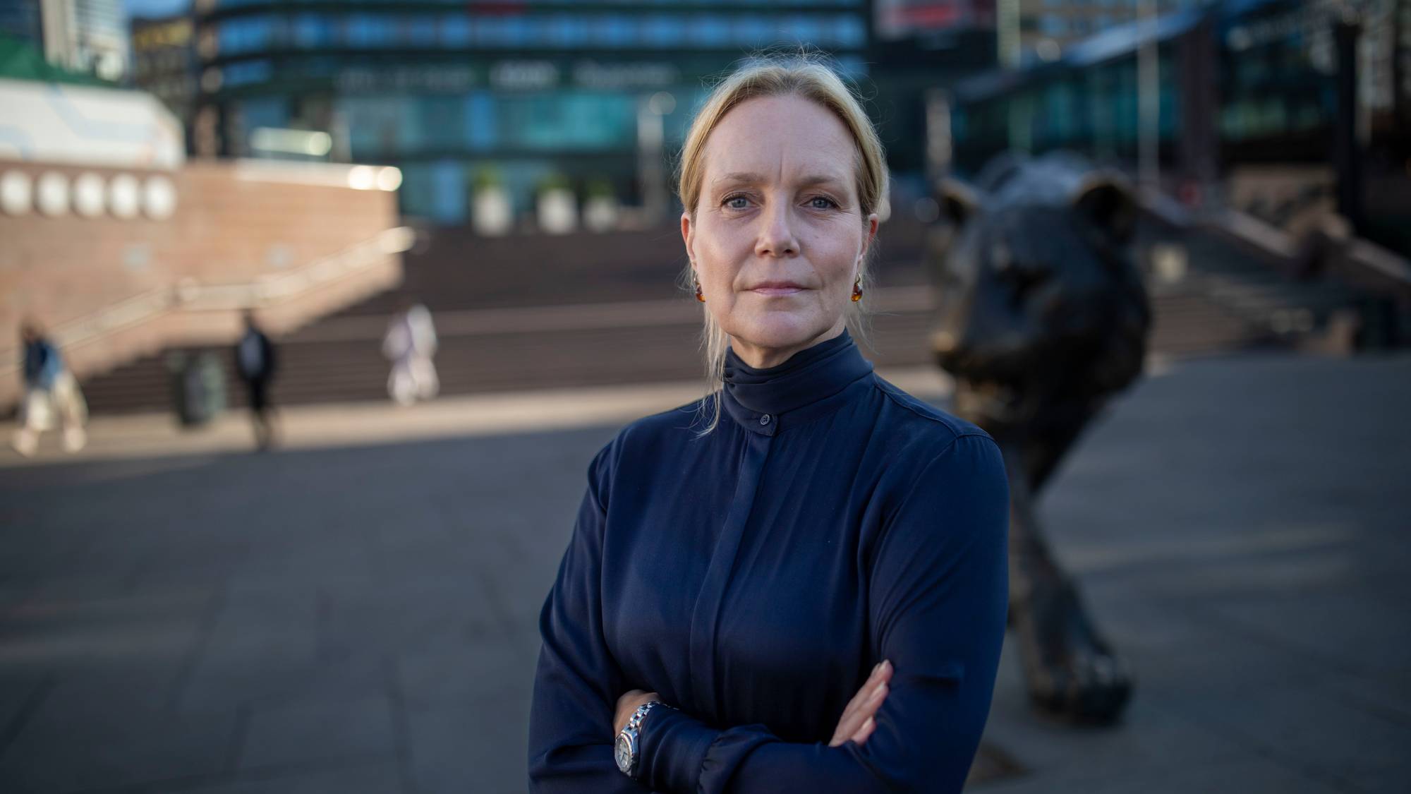 Kvinne med armene i kors står foran løvestatuen på Jernbanetorget i Oslo. (Bildebeskrivelsen er laget av en KI-tjeneste)