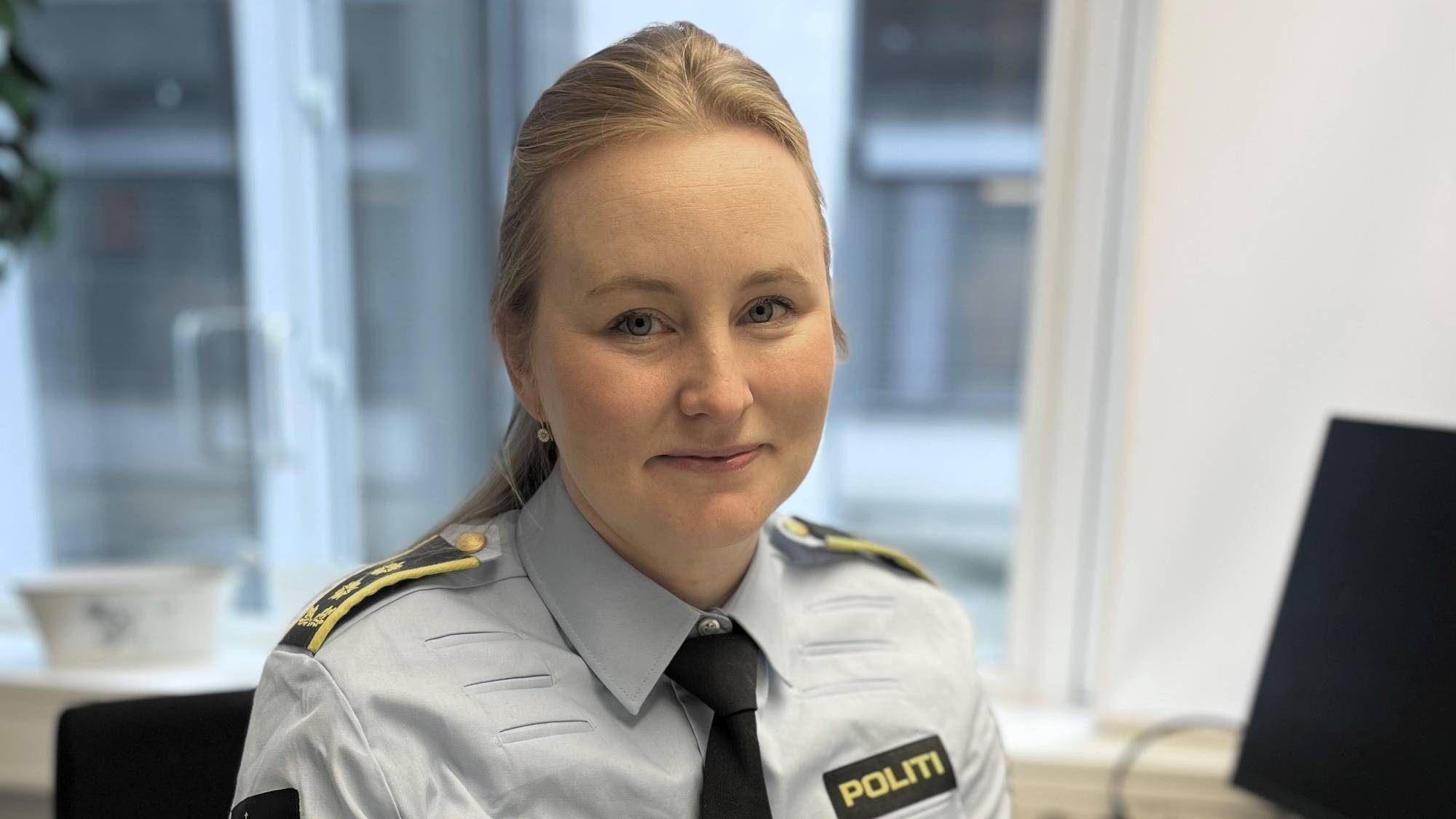 Politiadvokat Ingvild Ekaas, sitter smilende på kontorplass med tastatur og PC-skjerm.