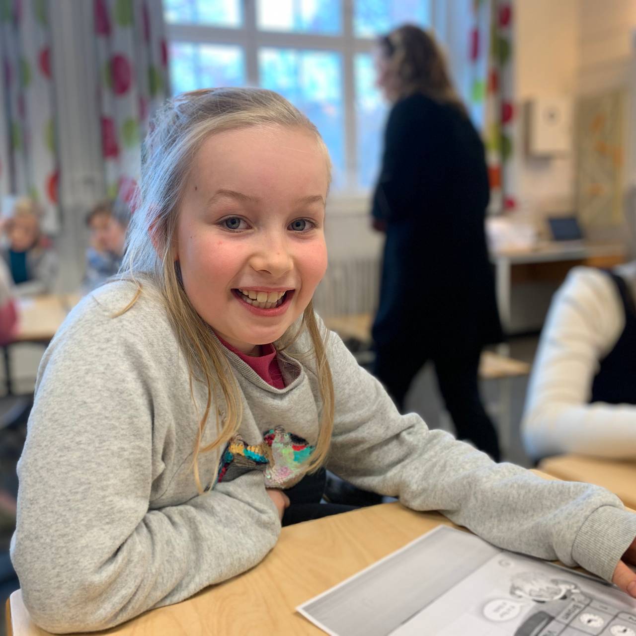 Hedvig sitter ved en pult i klasserommet.