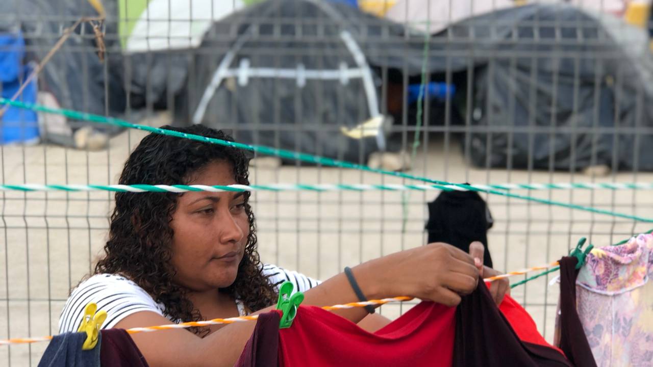 Kvinne henger opp klær i migrantleir på grensa mellom USA og Mexico