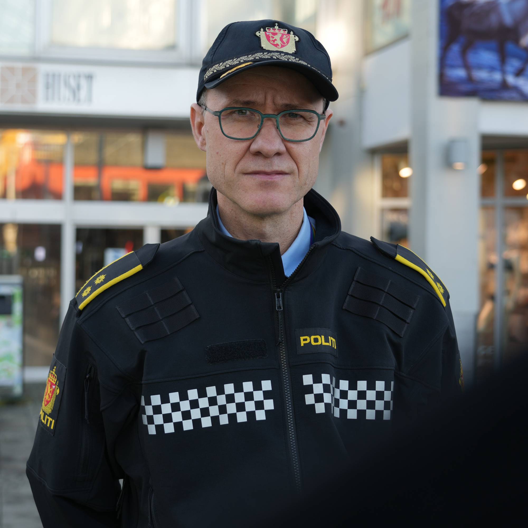 En politimann i uniform står foran inngangen til kjøpesenteret Glasshuset. (Bildebeskrivelsen er laget av en KI-tjeneste)