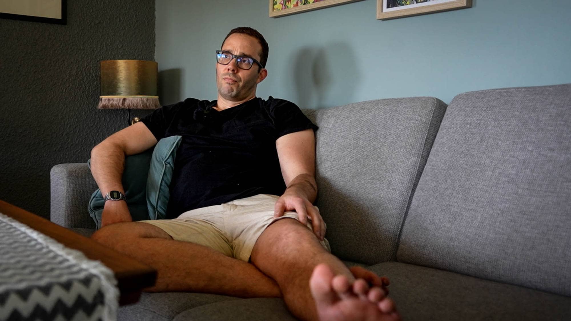Mann sitter i sofaen og forteller