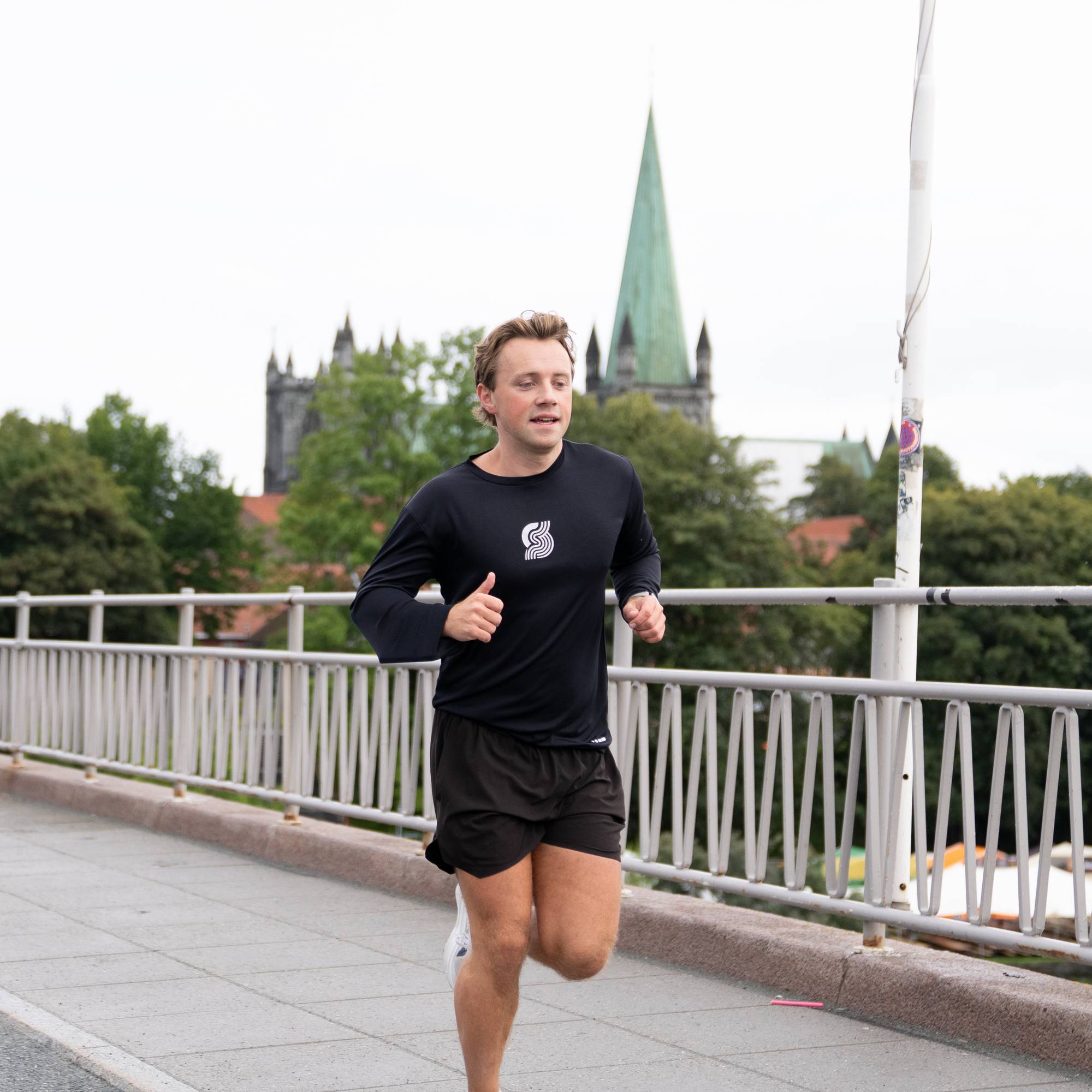 Odin Sørensen Tranås jogger over Elgseter bru i Trondheim. Nidarosdomen i bakgrunnen.