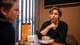 Foto: Frederik Ringnes / NRK To personer sitter ved et bord i en kafé. Den ene personen har en hånd på haken og ser på den andre. Det står en kopp med kaffe foran dem, samt en oppreist meny. Kaféens interiør er i varme farger med trepanel og naturlig belysning.