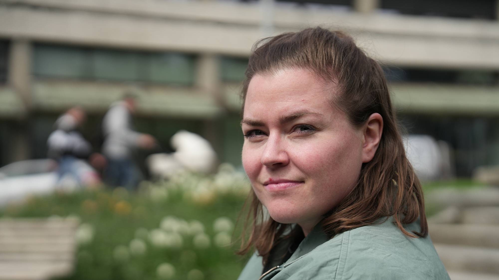 Kvinne som sitter på en benk i en park. 
