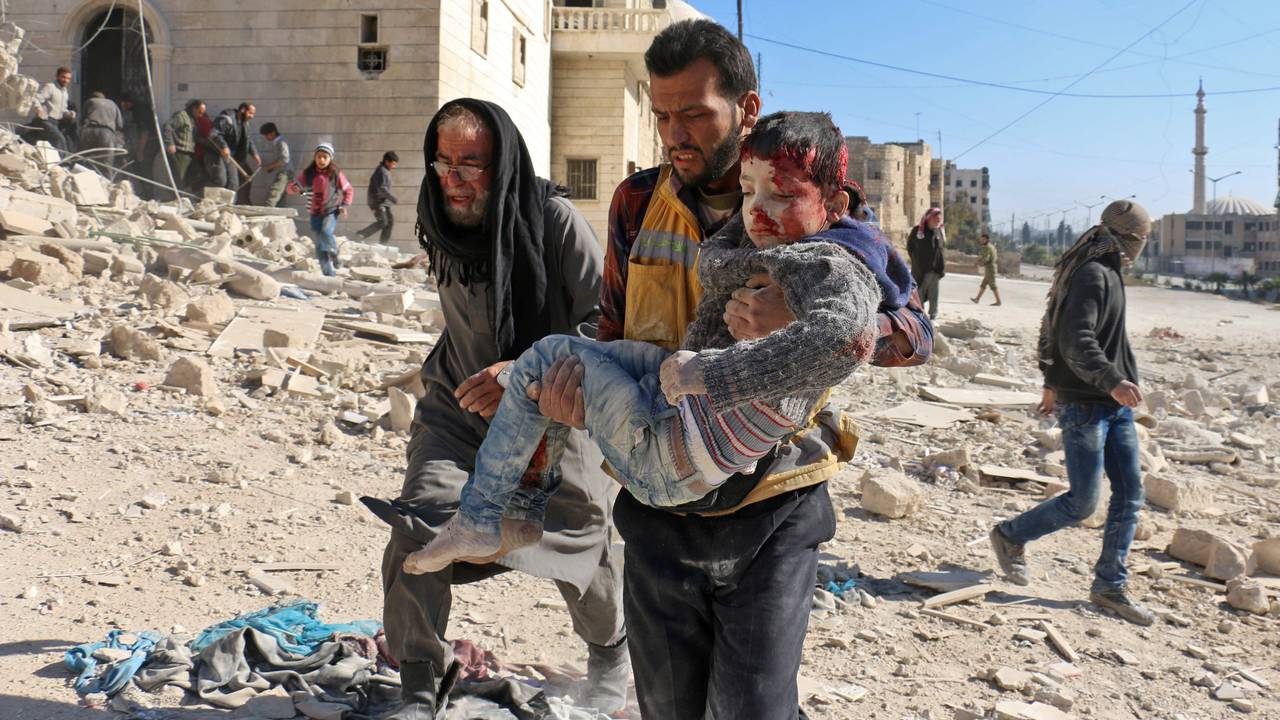 Et barn blir båret ut av ruinene etter et angivelig tønnebombeangrep i Aleppo.