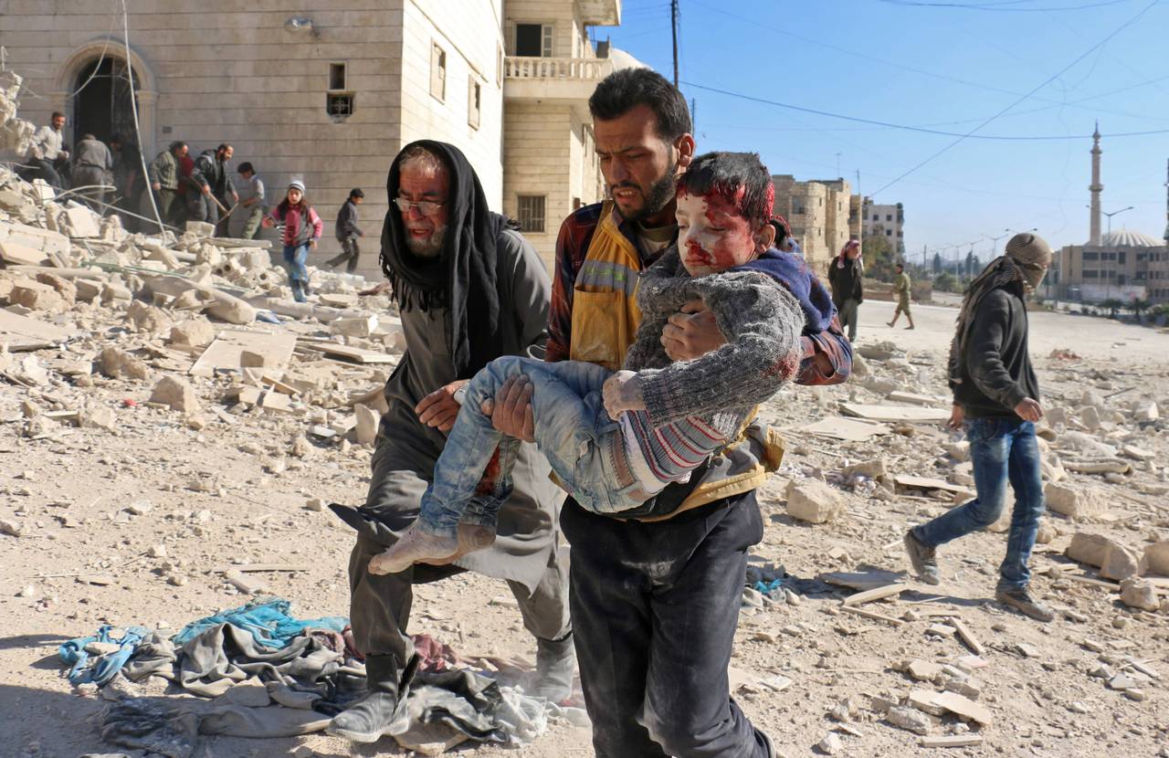 Et barn blir båret ut av ruinene etter et angivelig tønnebombeangrep i Aleppo. 