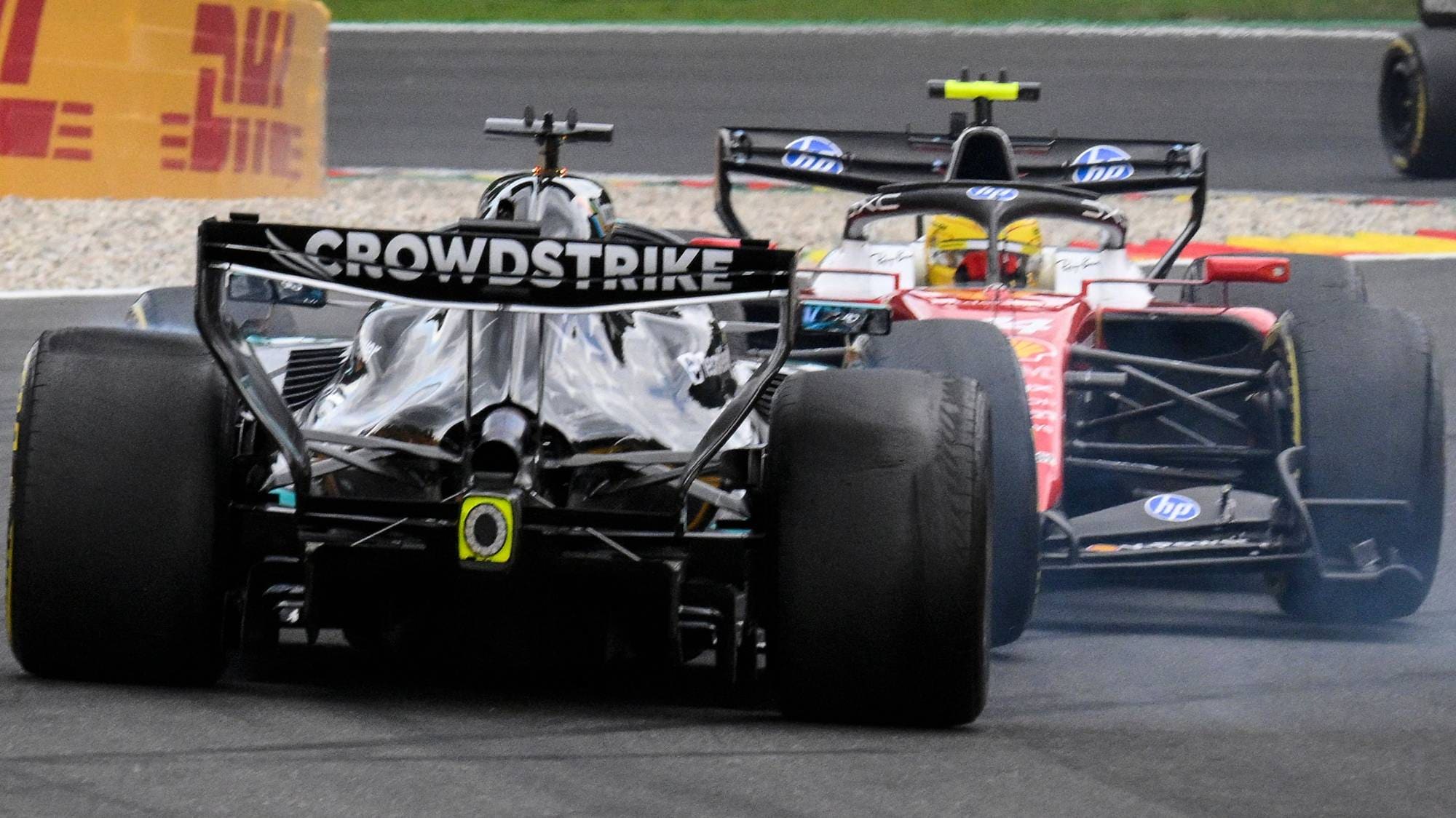 To Formel 1-biler kjører tett på en bane. (Bildebeskrivelsen er laget av en KI-tjeneste)