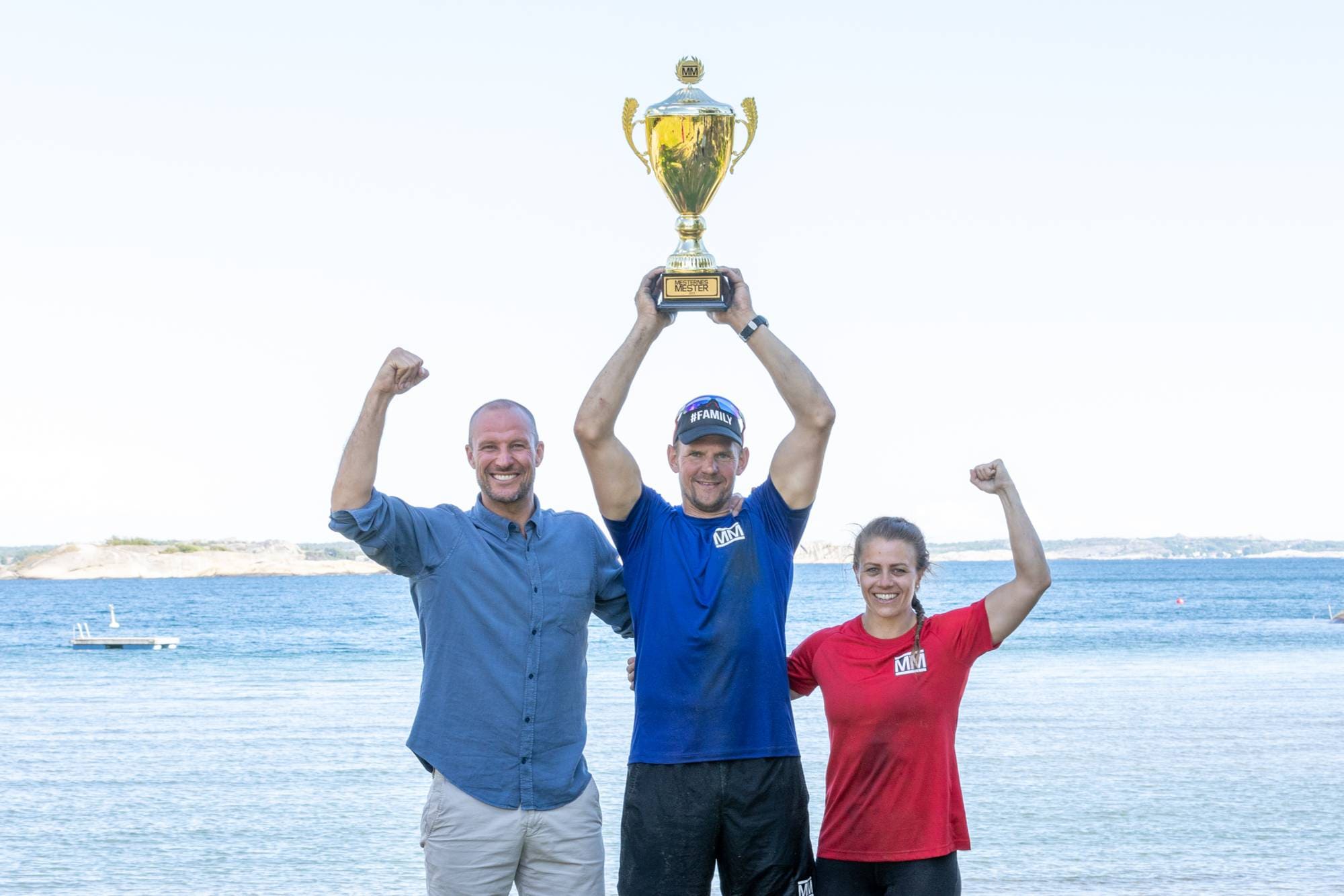 Vinner av Mesternes mester Olaf Tufte hever pokalen over hodet på stranda i Sandefjord, står mellom finalist Kristin Holte og programleder Aksel Lund Svindal