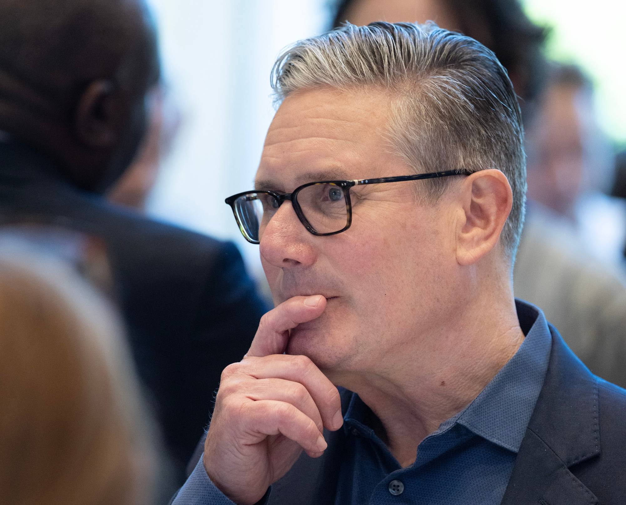 Keir Starmer nærfoto. Han ser mot venstre, holder en finger opp til munnen og ser ut som han tenker.
