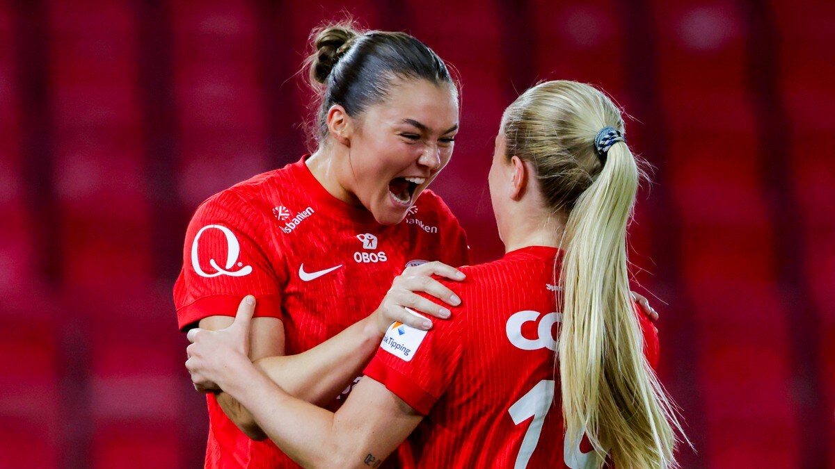 To kvinnelige fotballspillere i røde drakter feirer et mål med en klem på banen. (Bildebeskrivelsen er laget av en KI-tjeneste) FOTO: Paul S. Amundsen/NTB