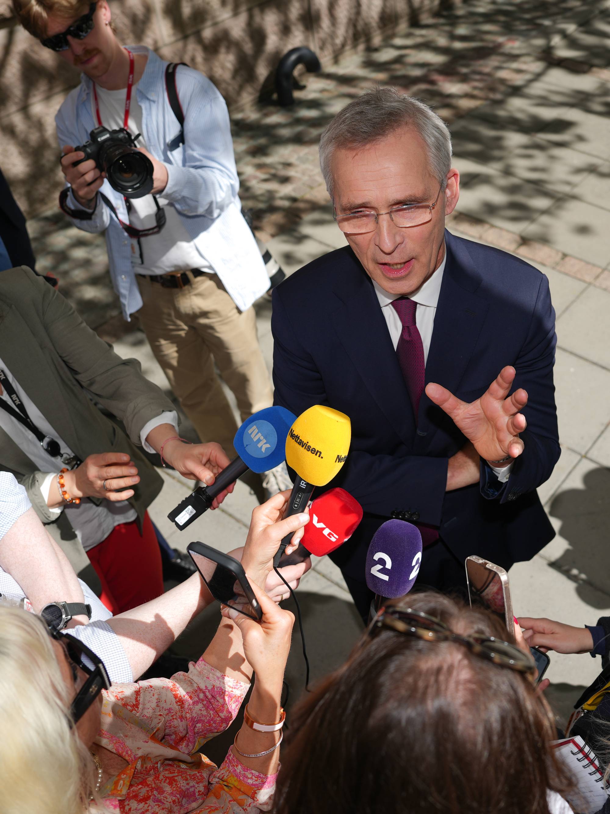en man i dress omringet av pressen snakker til dem og gestikulerer