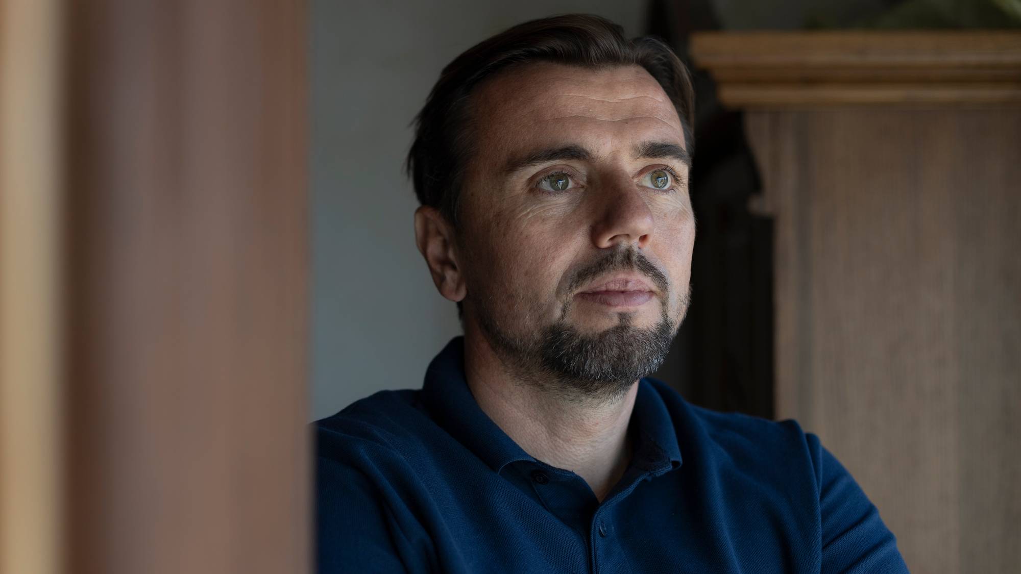 En mann med skjegg kikker ut i luften. Han har et fredelig blikk i ansiktet.