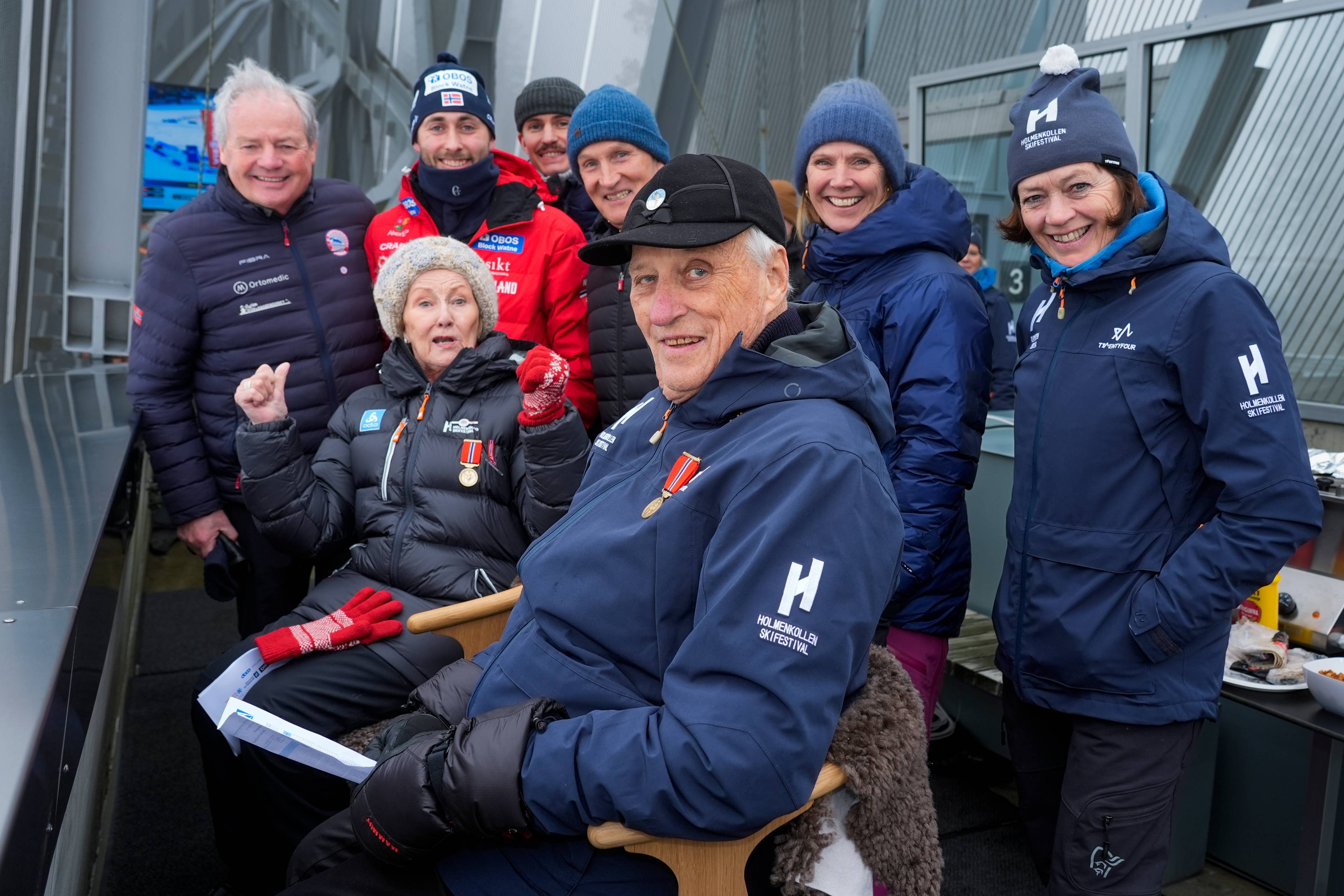 Kong Harald og dronning Sonja sammen med en gruppe mennesker i Holmenkollen. (Bildebeskrivelsen er laget av en KI-tjeneste)