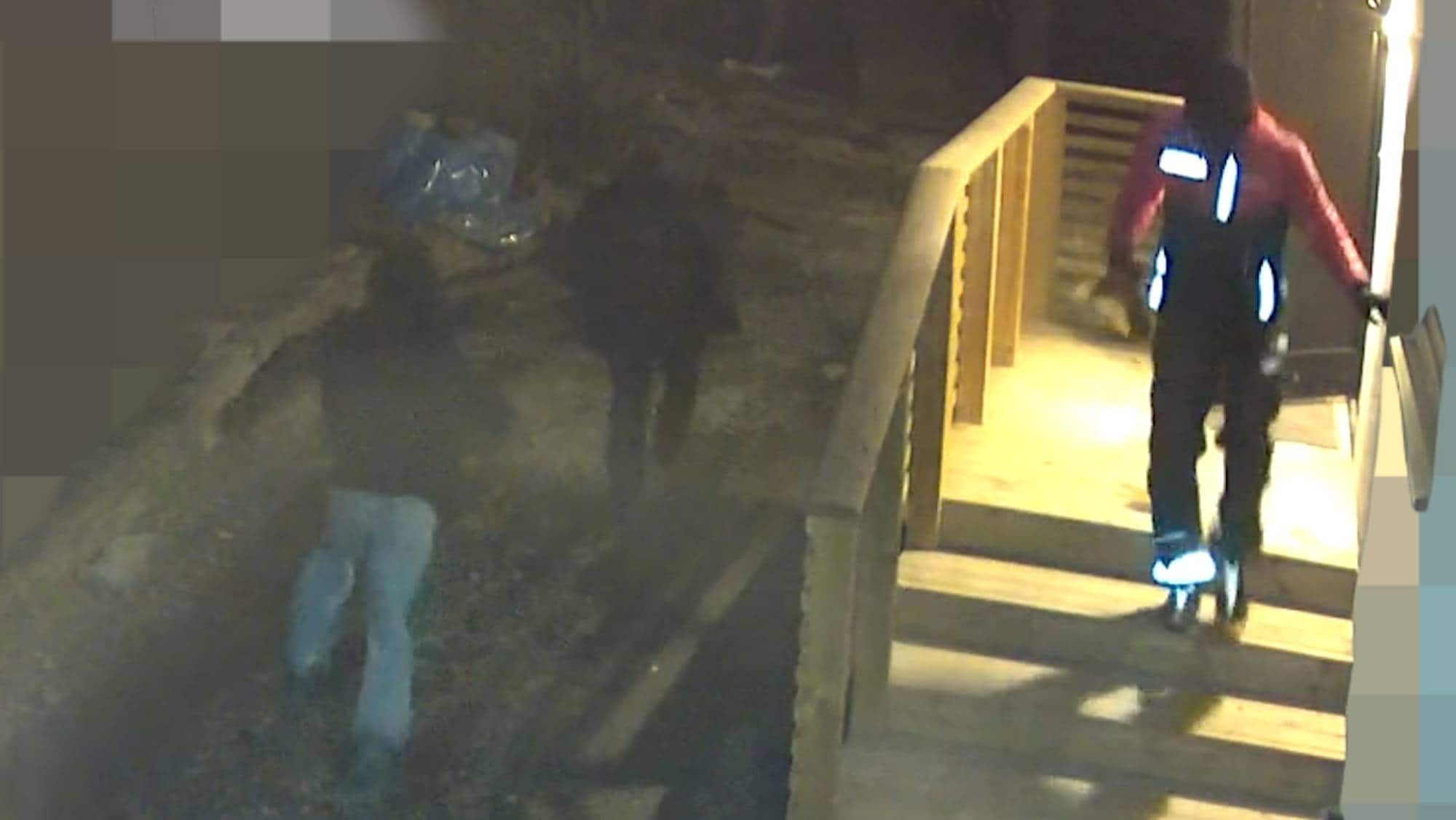 Bildet viser tre personer som forsvinner fra et hus. To av dem har mørke jakker og hette på hodet. 