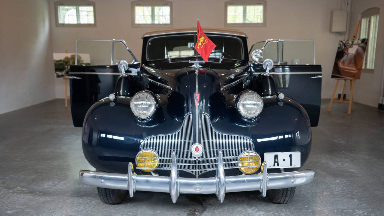 A1 står parkert med dørene åpne og kongeflagget foran på bilen