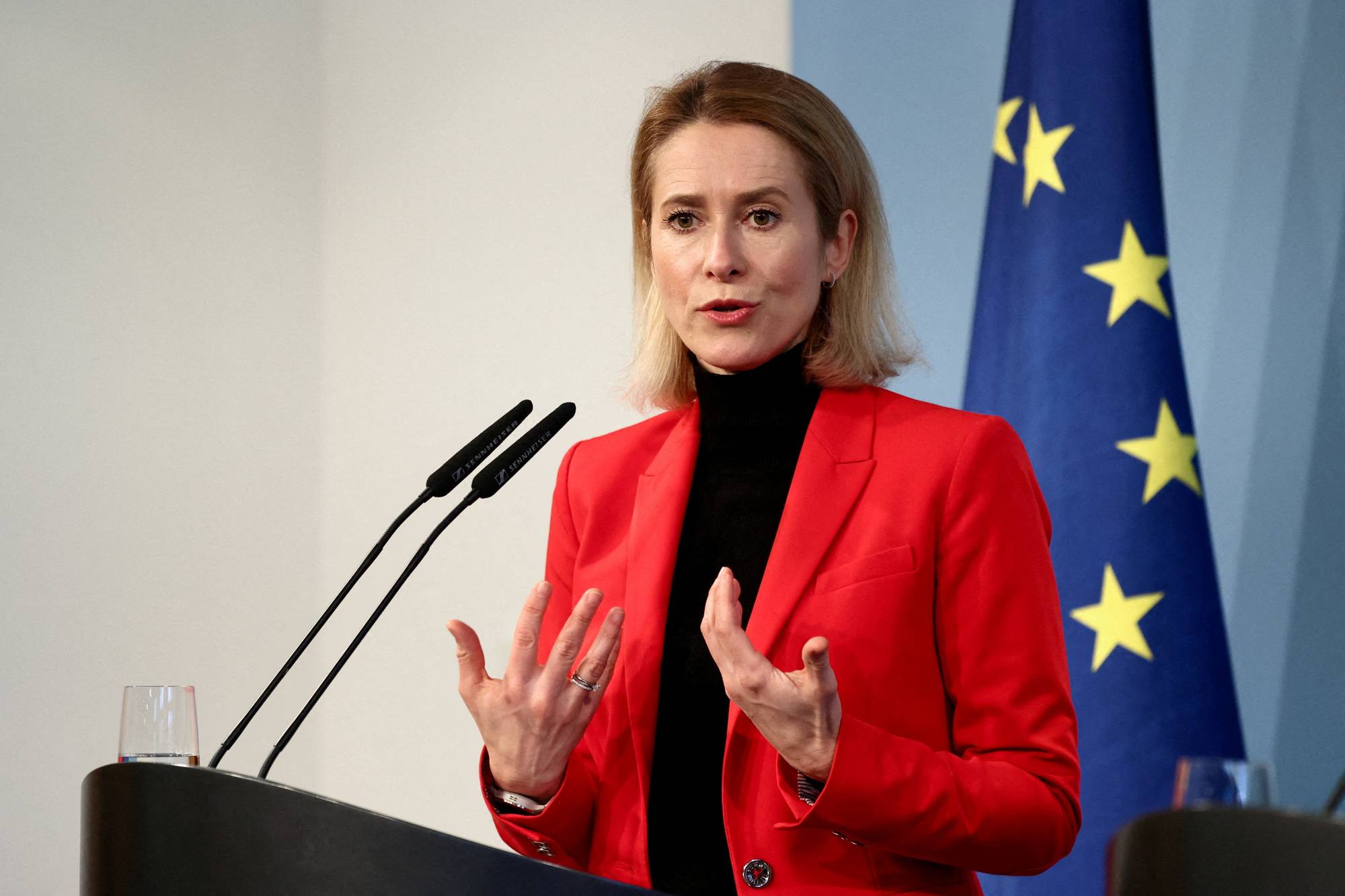 Kaja Kallas holder tale foran EU-flagget. Hun bærer rød blazer og sort pologenser. (Bildebeskrivelsen er laget av en KI-tjeneste)