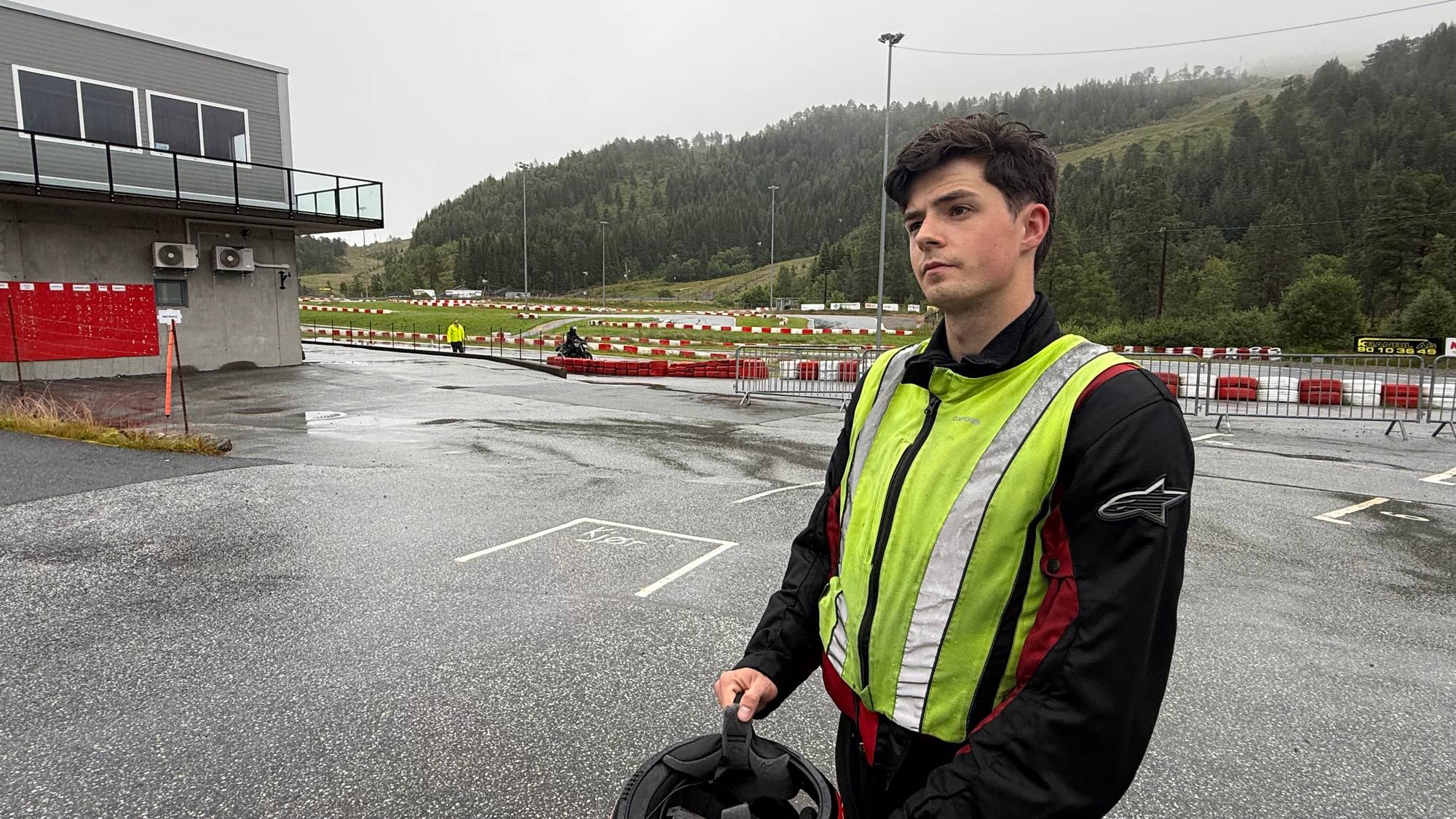 mann i gul og svart jakke med mc-hjelm i handa