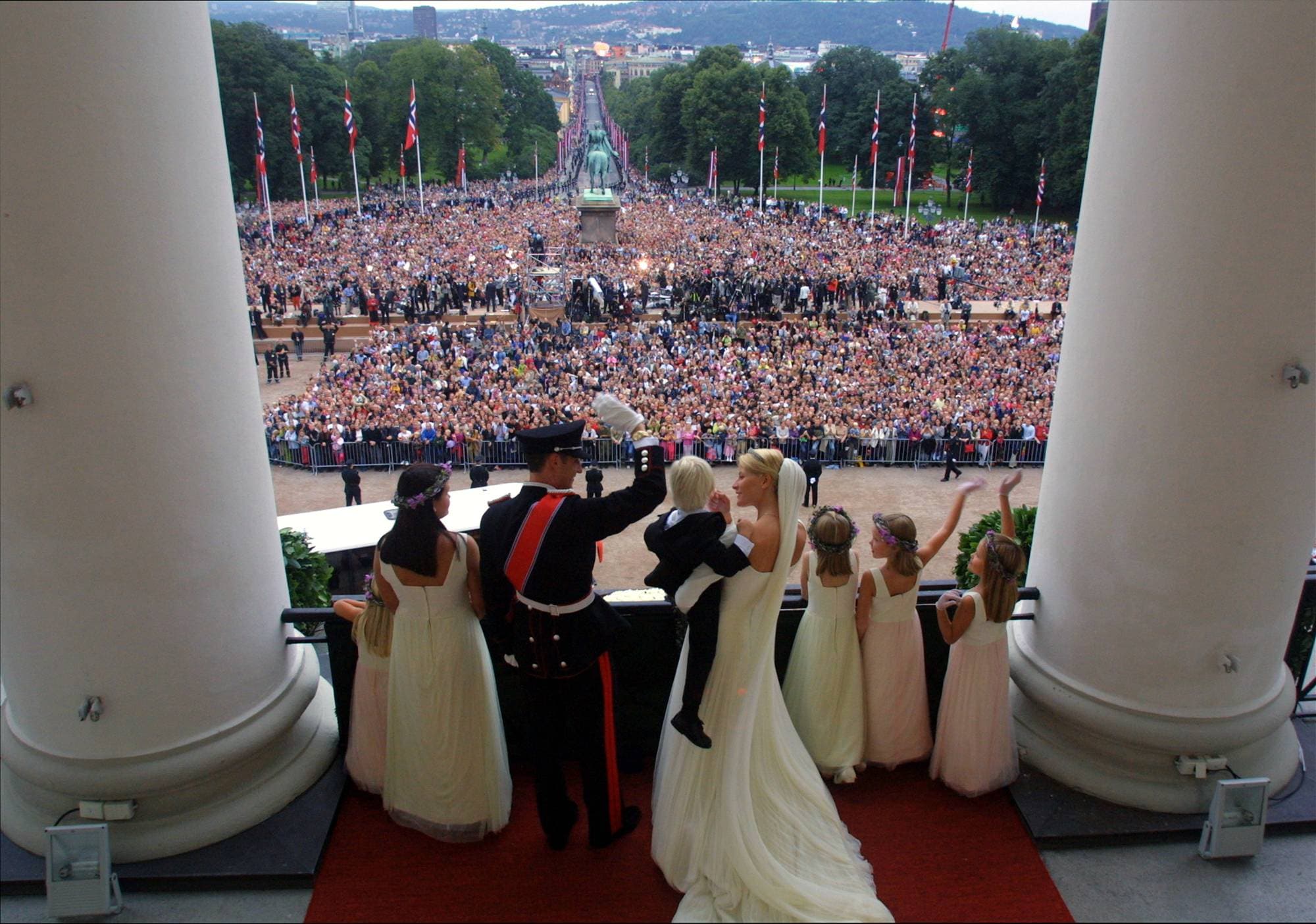 Kronprinsesse Mette-Marit holder Marius på armen mens hun og kronprins Haakon står på Slottsbalkongen og vinker til folkehavet på Slottsplassen etter kronprinsparets bryllup 25. august 2001