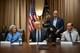 MANDEL NGAN / AFP / NTB Bilde viser en gruppe personer samlet rundt et bord i et møterom. Det er en mann i sentrum med hvitt hår, iført dress, som står foran et dokument. Bak mennene henger to amerikanske flagg, og det er andre personer til stede som ser mot kameraet. Omgivelsene inkluderer brune gardiner og en klokke synlig på veggen. (Bildebeskrivelsen er laget av en KI-tjeneste)