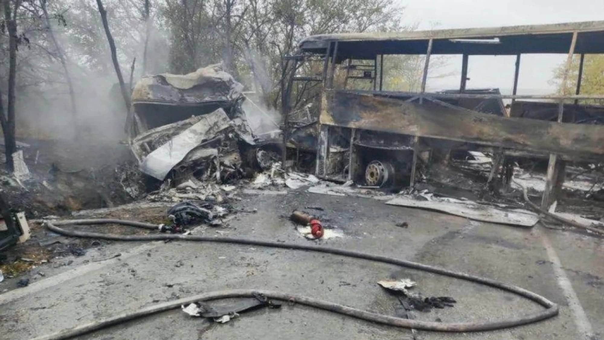 Utbrent buss og vrak etter trafikkulykke. Brannslanger ligger på bakken ved siden av vraket. (Bildebeskrivelsen er laget av en KI-tjeneste)