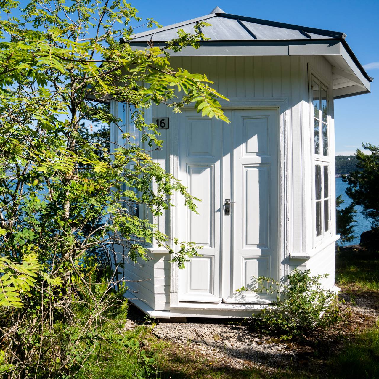 På en holme ut mot sjøen på Malmøykalven står et hvitt lysthus idyllisk plassert.