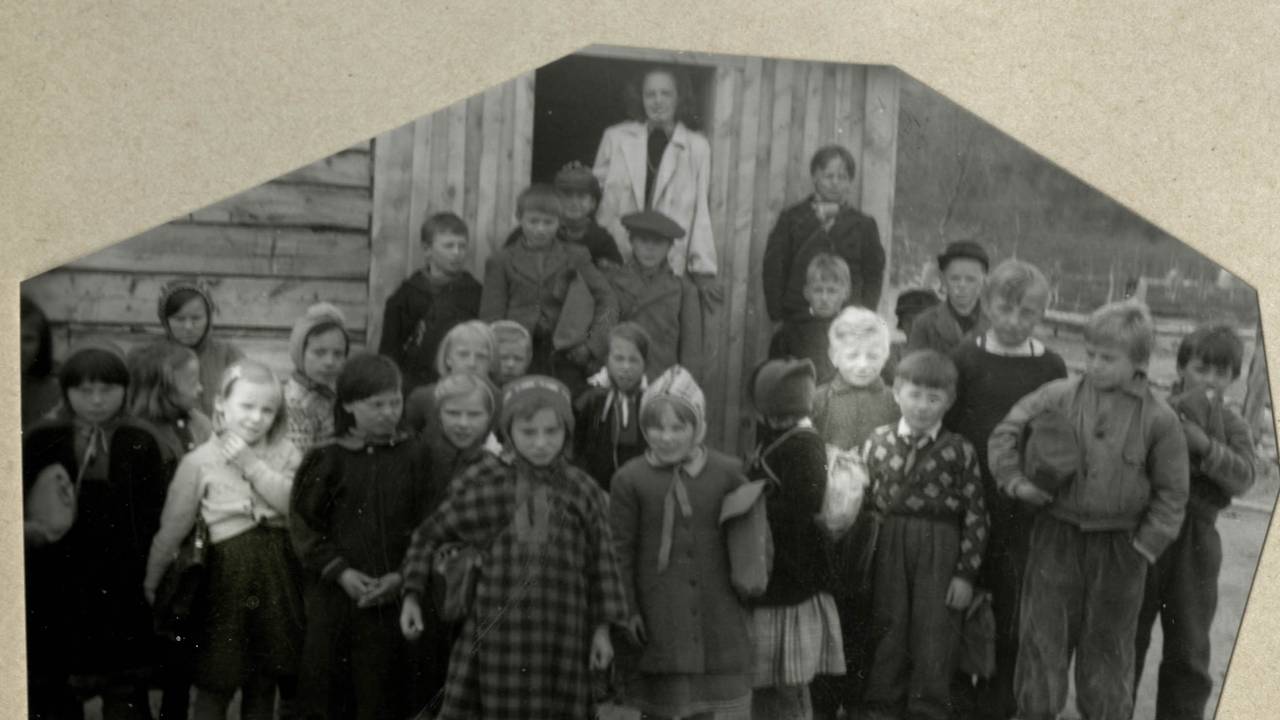 En liten jente og en liten gutt mellom andre barn på et klassebilde