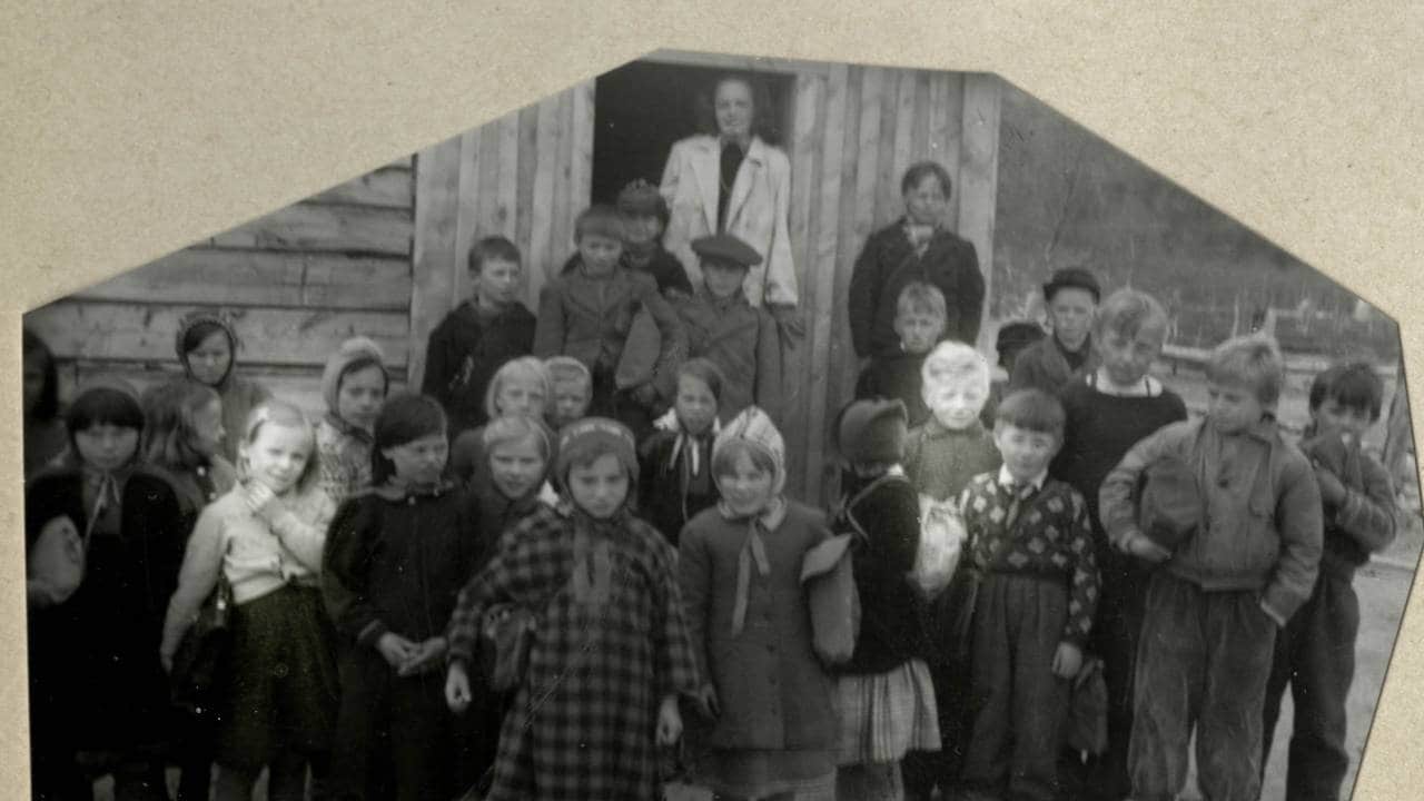 En liten jente og en liten gutt mellom andre barn på et klassebilde