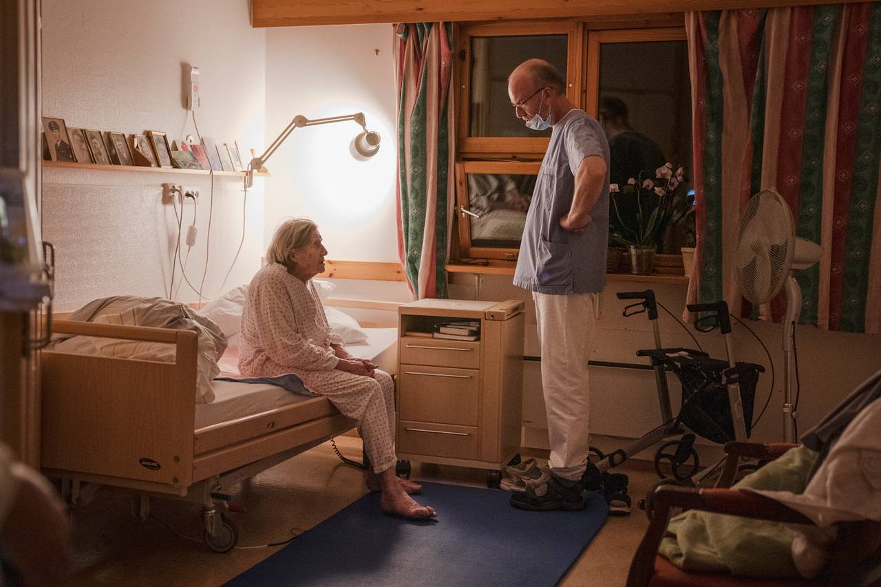 Eugenia sitter i sengen og møter blikket til nattevakten som står og ser litt bestemt på henne fra midt i rommet.