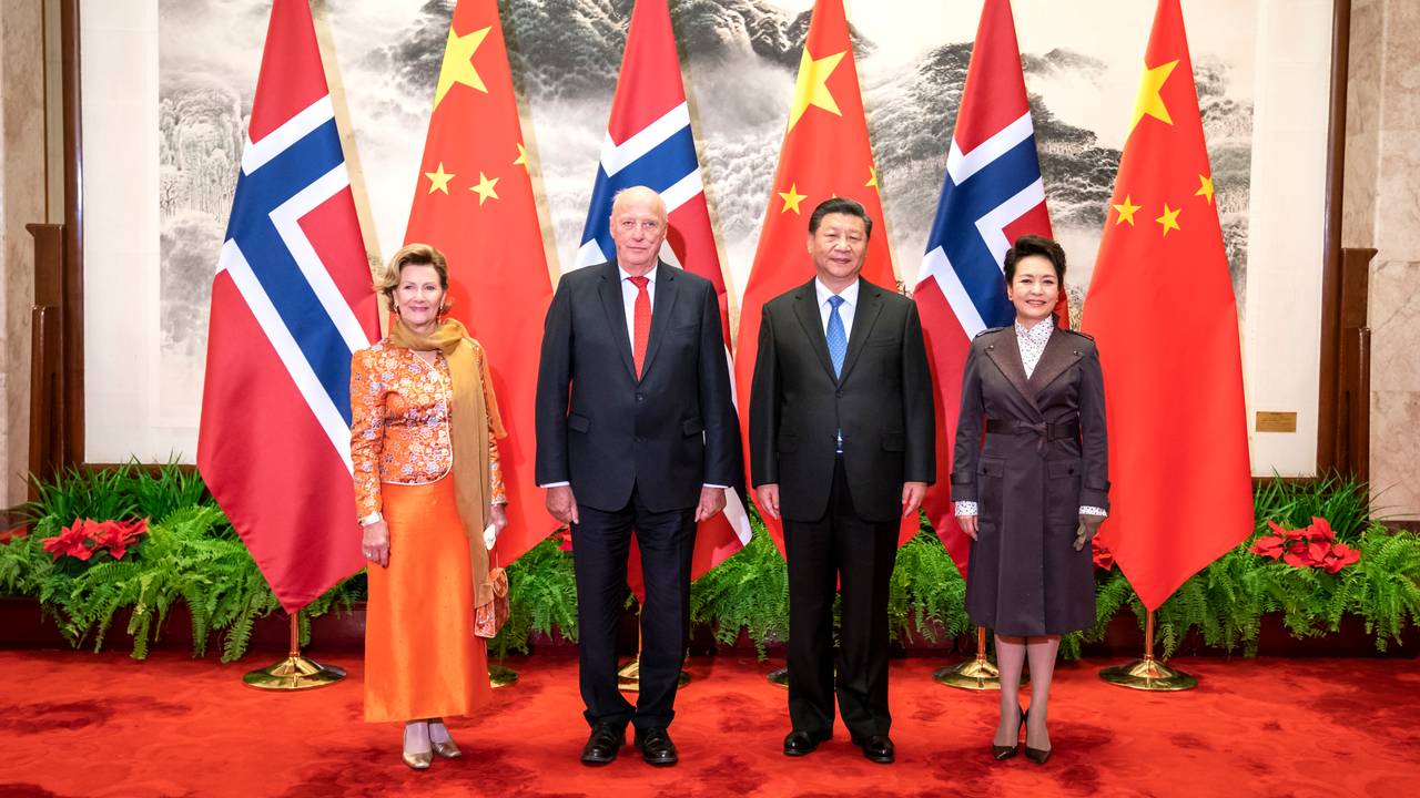 Dronning Sonja og kong Harald står sammen med Kinas president Xi Jinping og kona Peng Liyuan foran norske og kinesiske flagg.